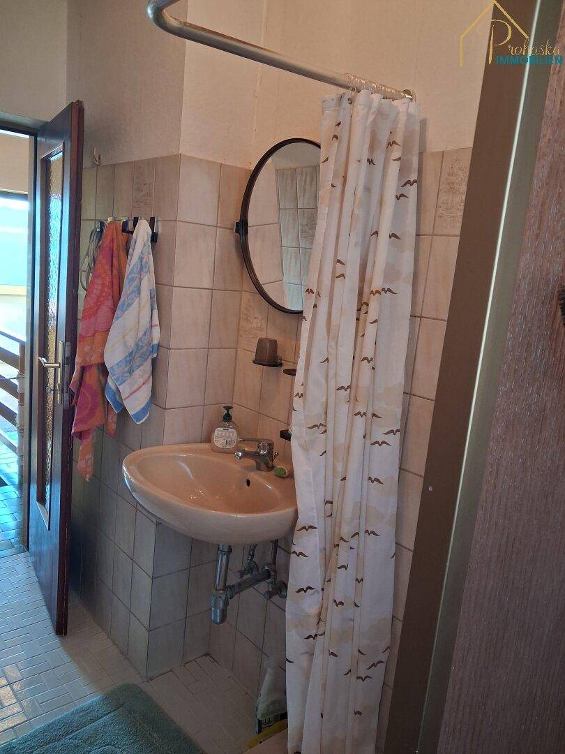 Badezimmer mit Waschbecken, Spiegel und Duschvorhang.
