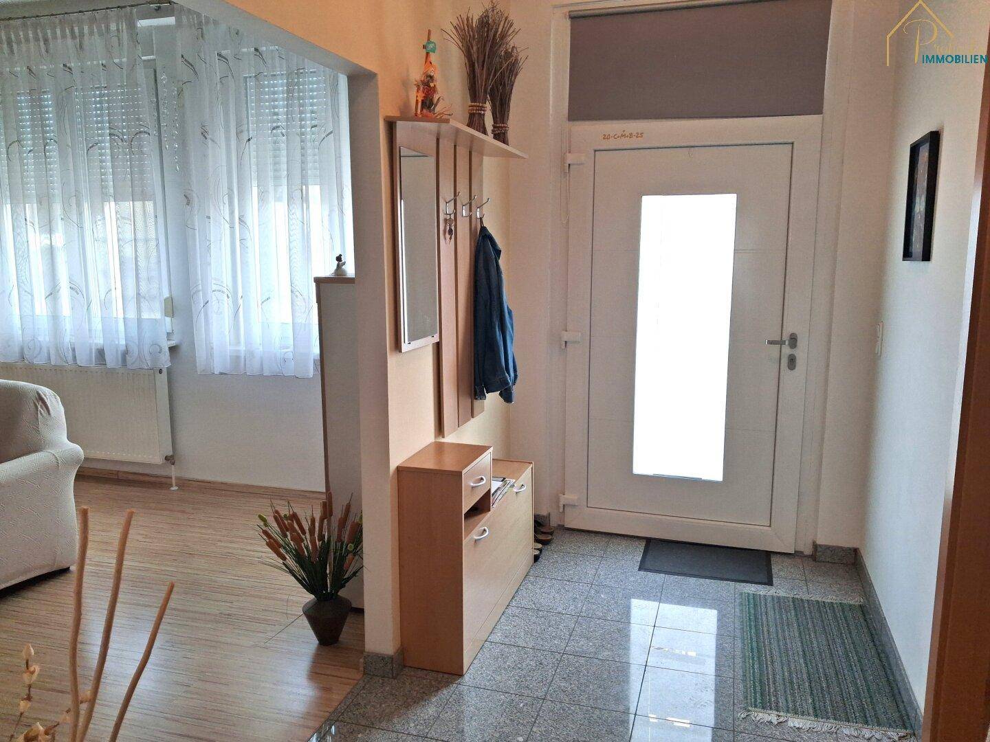 Heller Eingangsbereich mit Garderobe, Schuhschrank und gefliestem Boden.