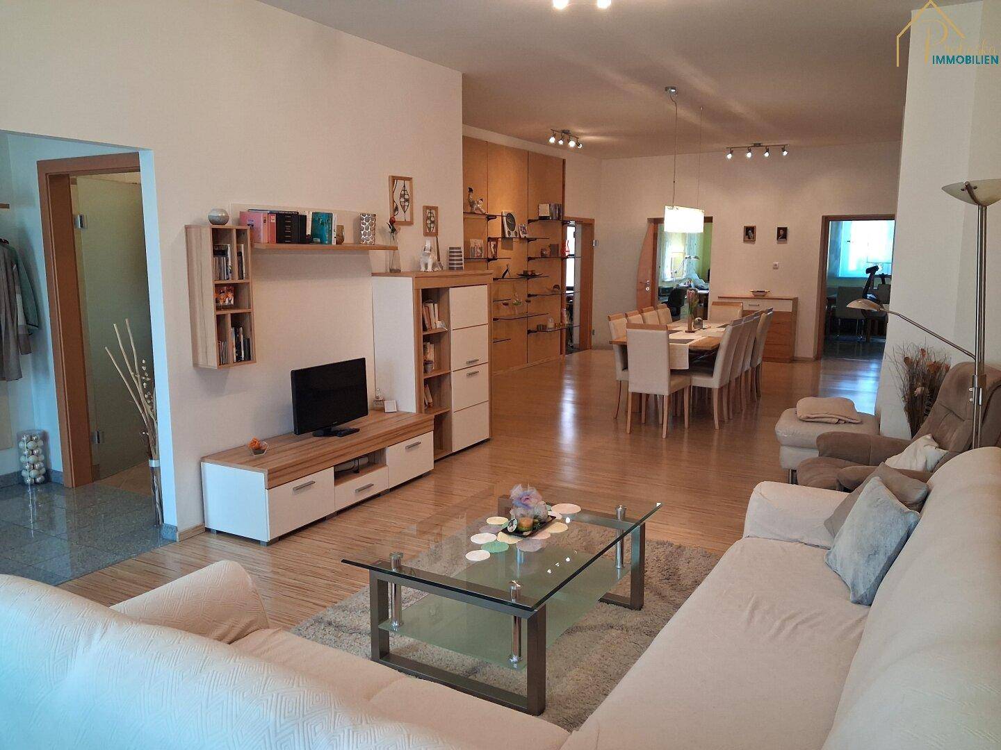 Gemütlicher Wohnbereich mit Sofa, Couchtisch und Blick auf den Essbereich im Hintergrund.