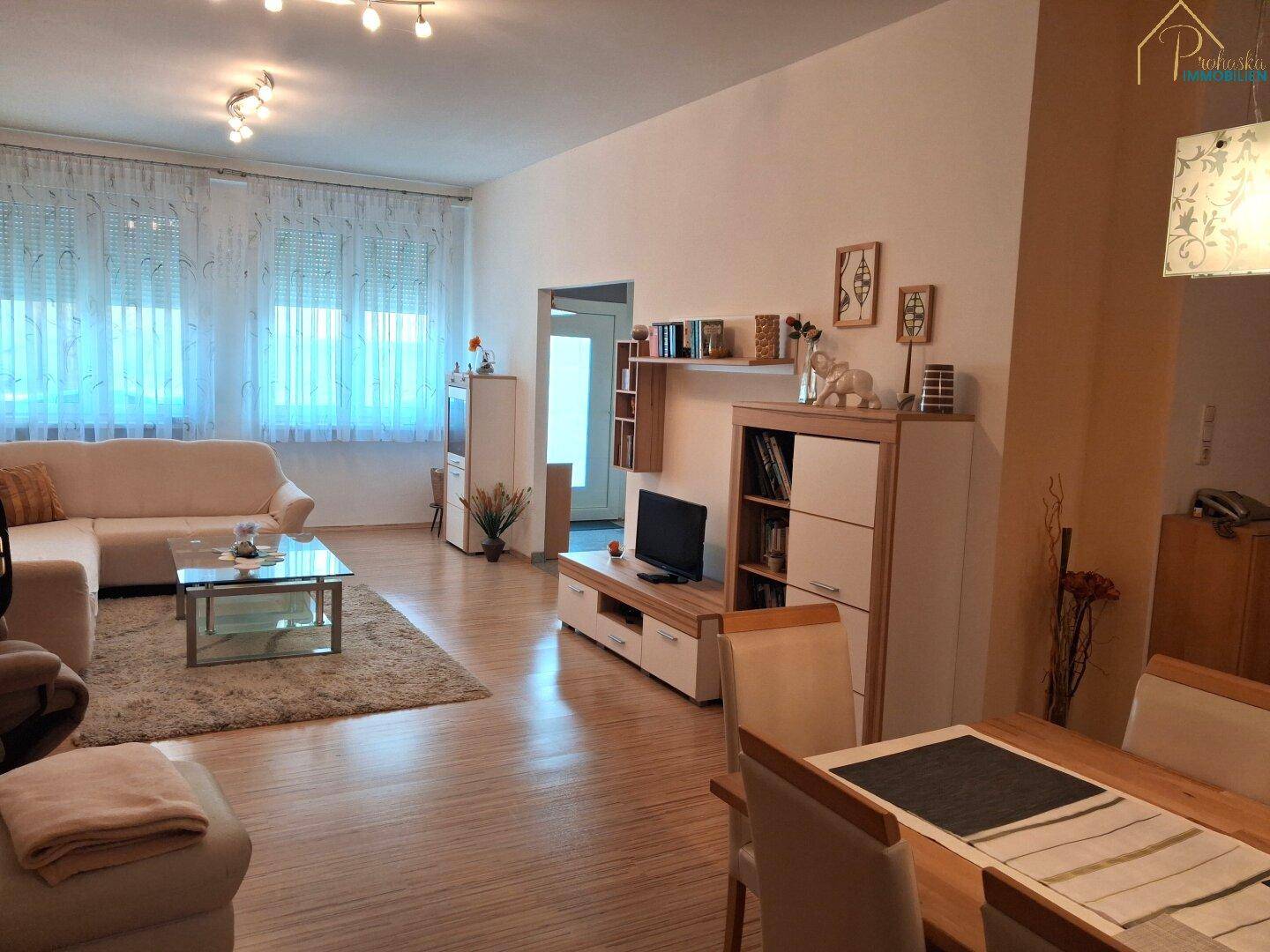 Heller Wohnbereich mit Sofa, TV-Möbeln und Blick auf den angrenzenden Essbereich.