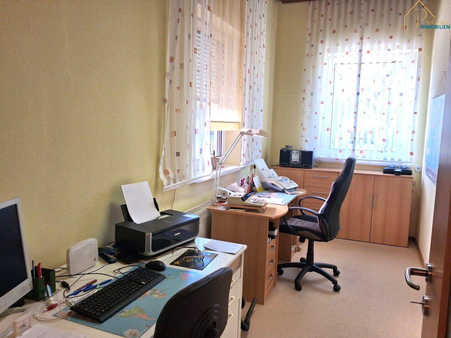 Helles Arbeitszimmer mit zwei Schreibtischen, Bürostühlen und großem Fenster.