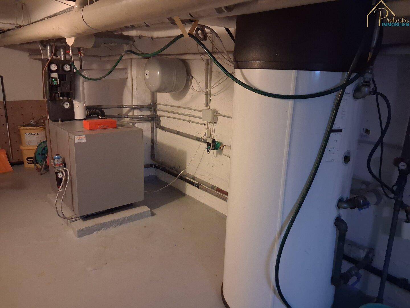 Heizungsraum im Keller mit moderner Heizungsanlage und Warmwasserspeicher.