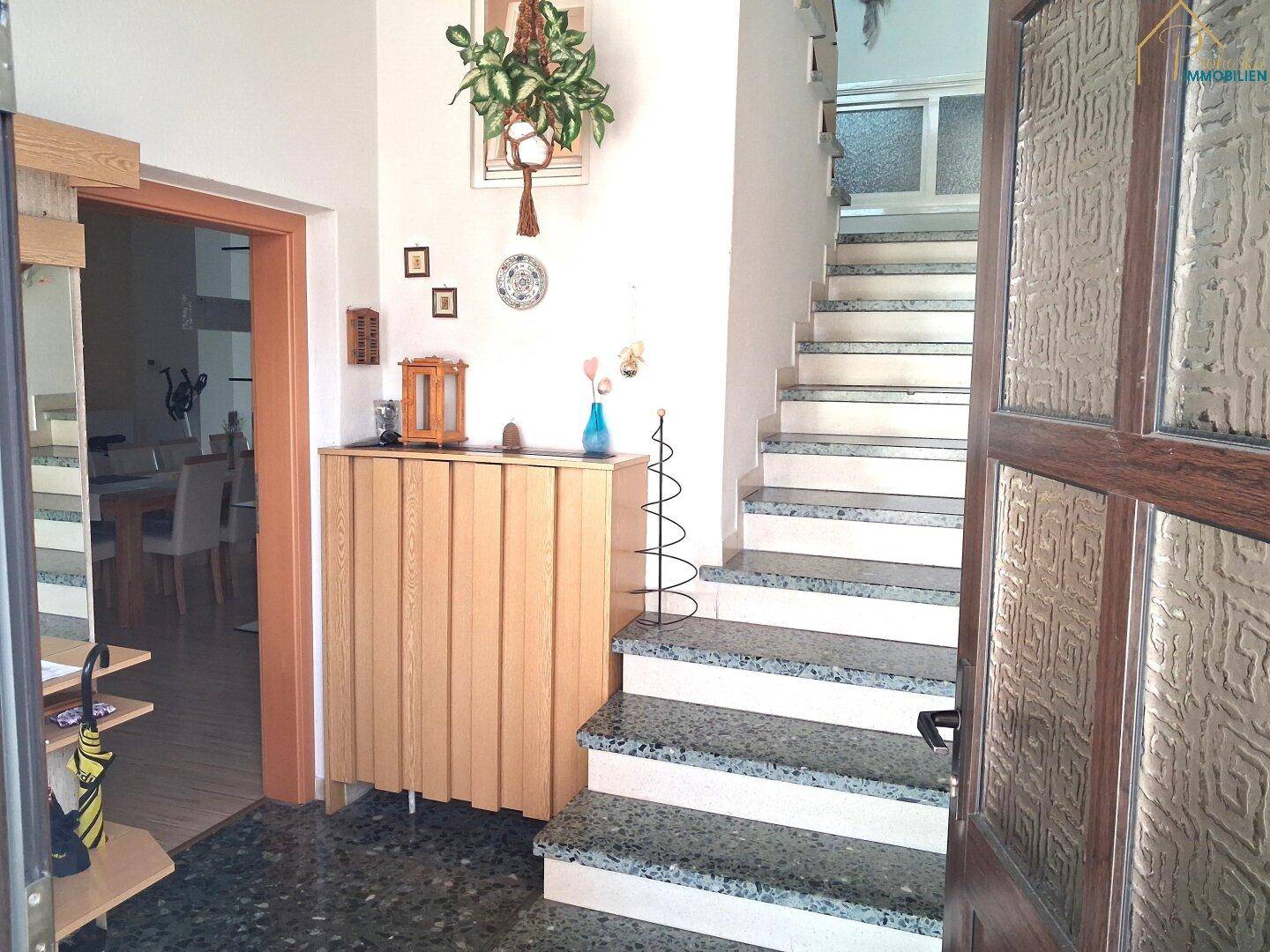 Eingangsbereich mit Treppe zum Obergeschoss und gefliestem Boden.