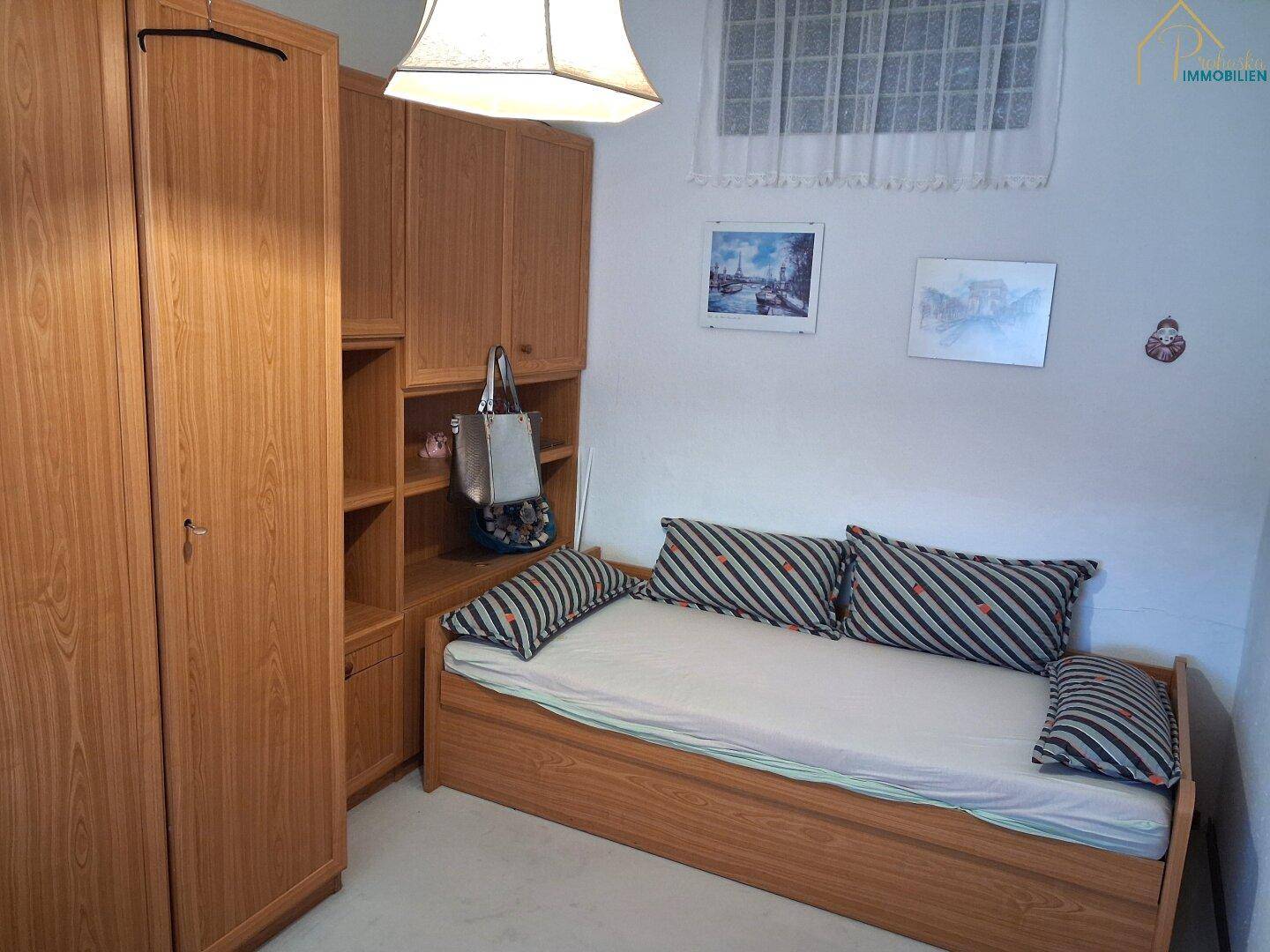 Schlafzimmer mit Einzelbett und Holzschrank, ideal als Kinder- oder Gästezimmer.