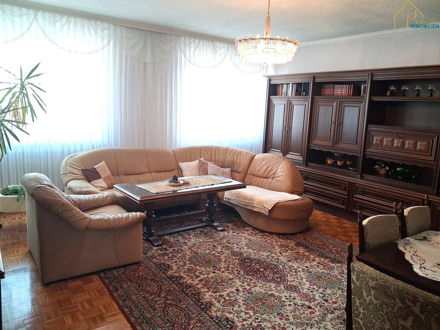 Klassisches Wohnzimmer mit Ledersofa, Teppich und großer Holzschrankwand.