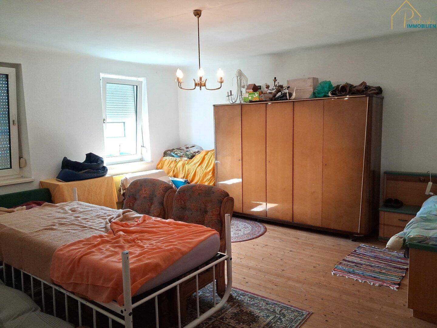 Schlafzimmer mit Holzboden, mehreren Betten und einem großen Kleiderschrank.