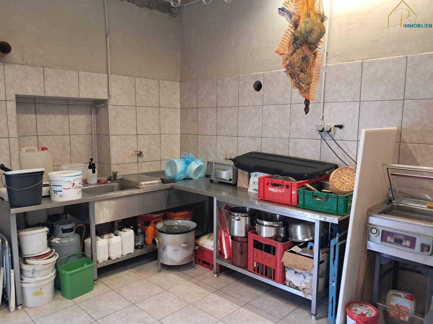 Einfache Küche oder Wirtschaftsraum mit Edelstahlspüle und Arbeitsflächen.