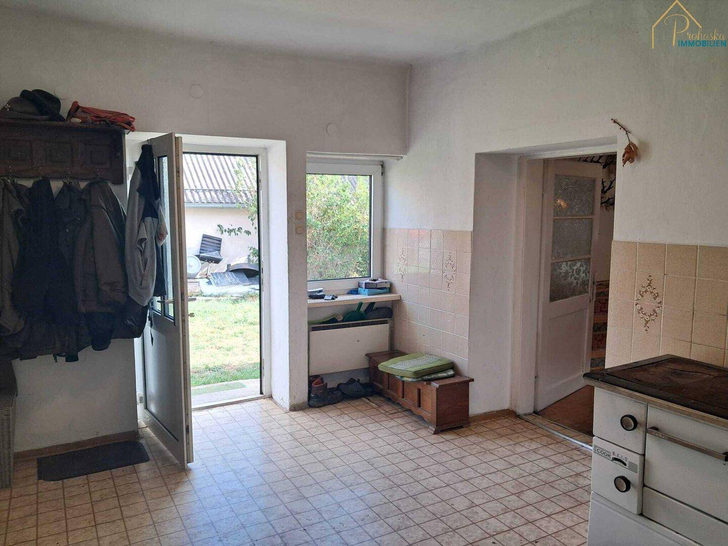 Eingangsbereich mit Fliesenboden, Garderobe und Zugang zum Garten.