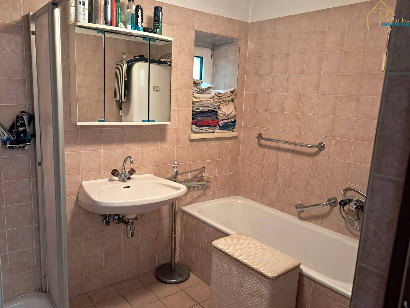 Badezimmer mit rosa Fliesen, Waschbecken, Badewanne und Duschkabine.