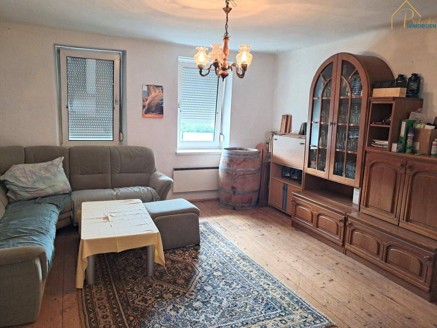 Gemütliches Wohnzimmer mit Holzboden, Sofa und traditionellem Holzschrank.