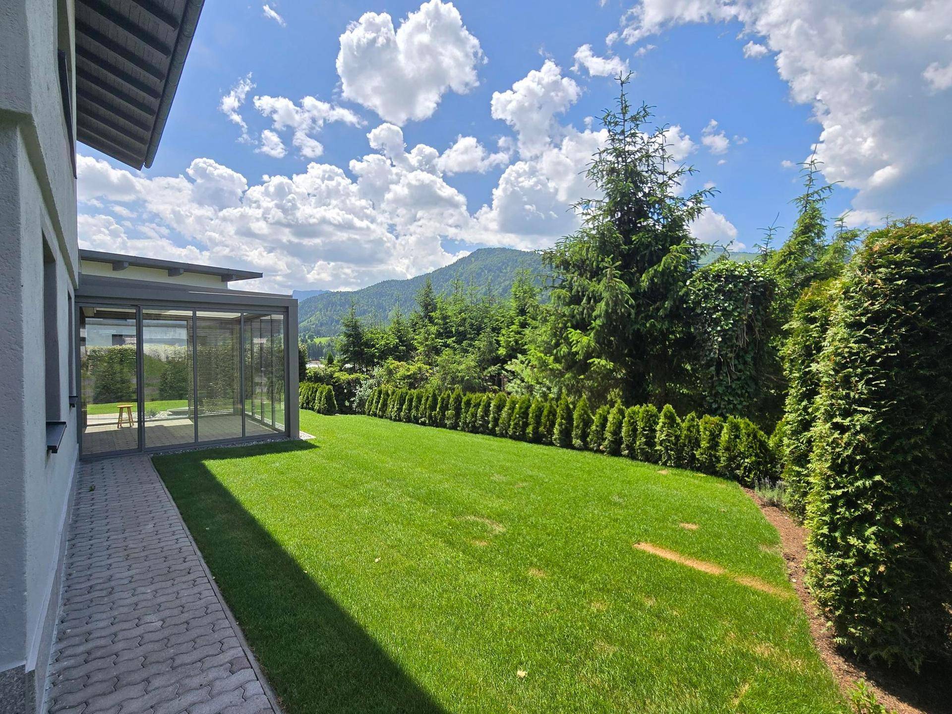 Großer, gepflegter Garten mit Hecke und Panoramablick auf die Berge.