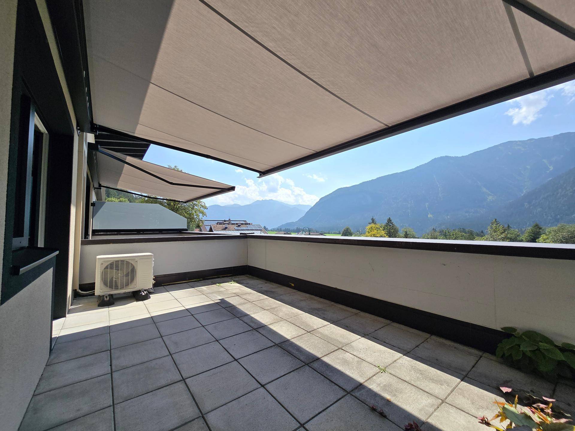 Große geflieste Terrasse mit Markisen, Klimaanlage und beeindruckendem Bergblick.