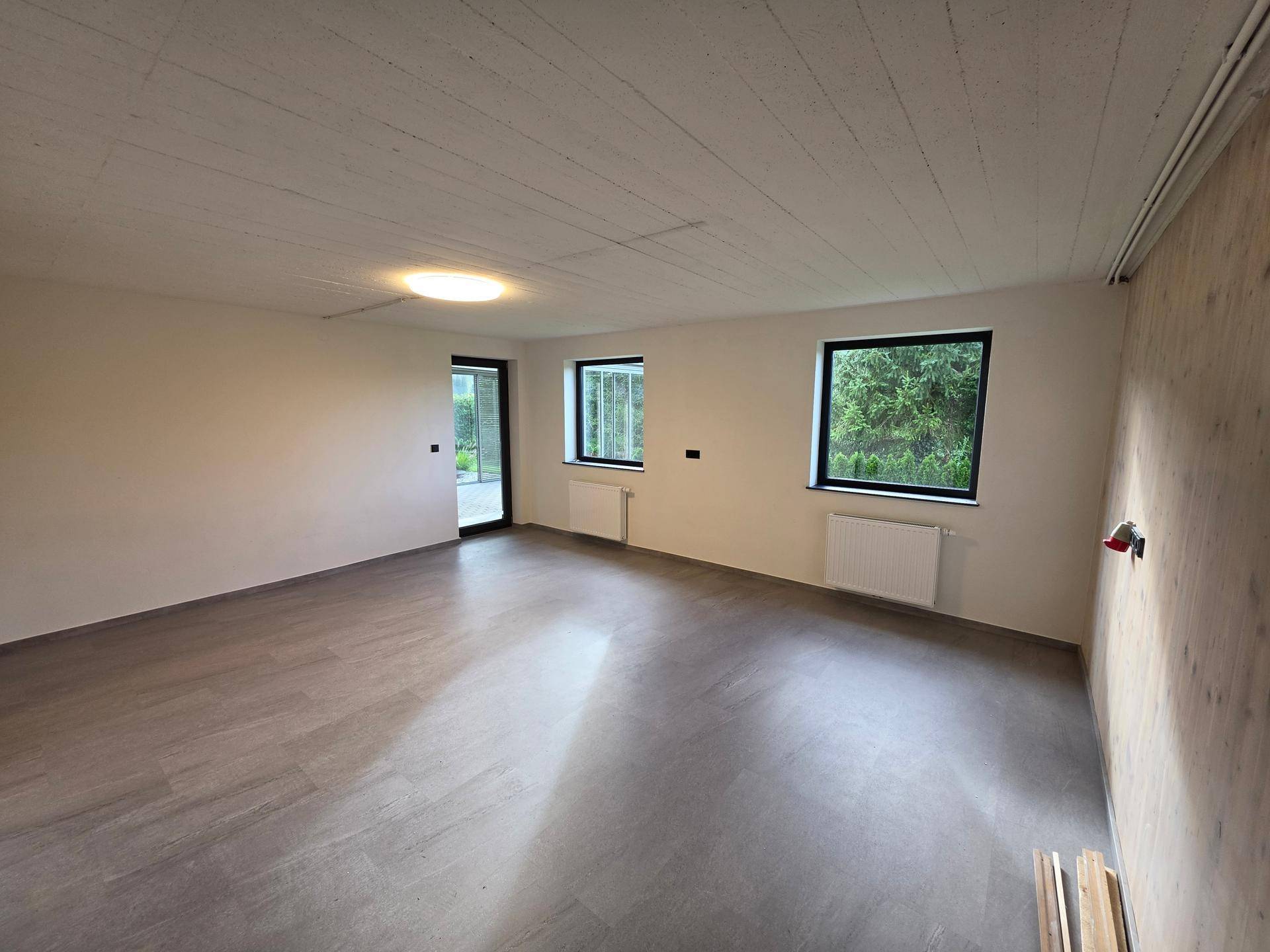 Geräumiger Mehrzweckraum im Untergeschoss mit Fliesenboden und Zugang zum Außenbereich.