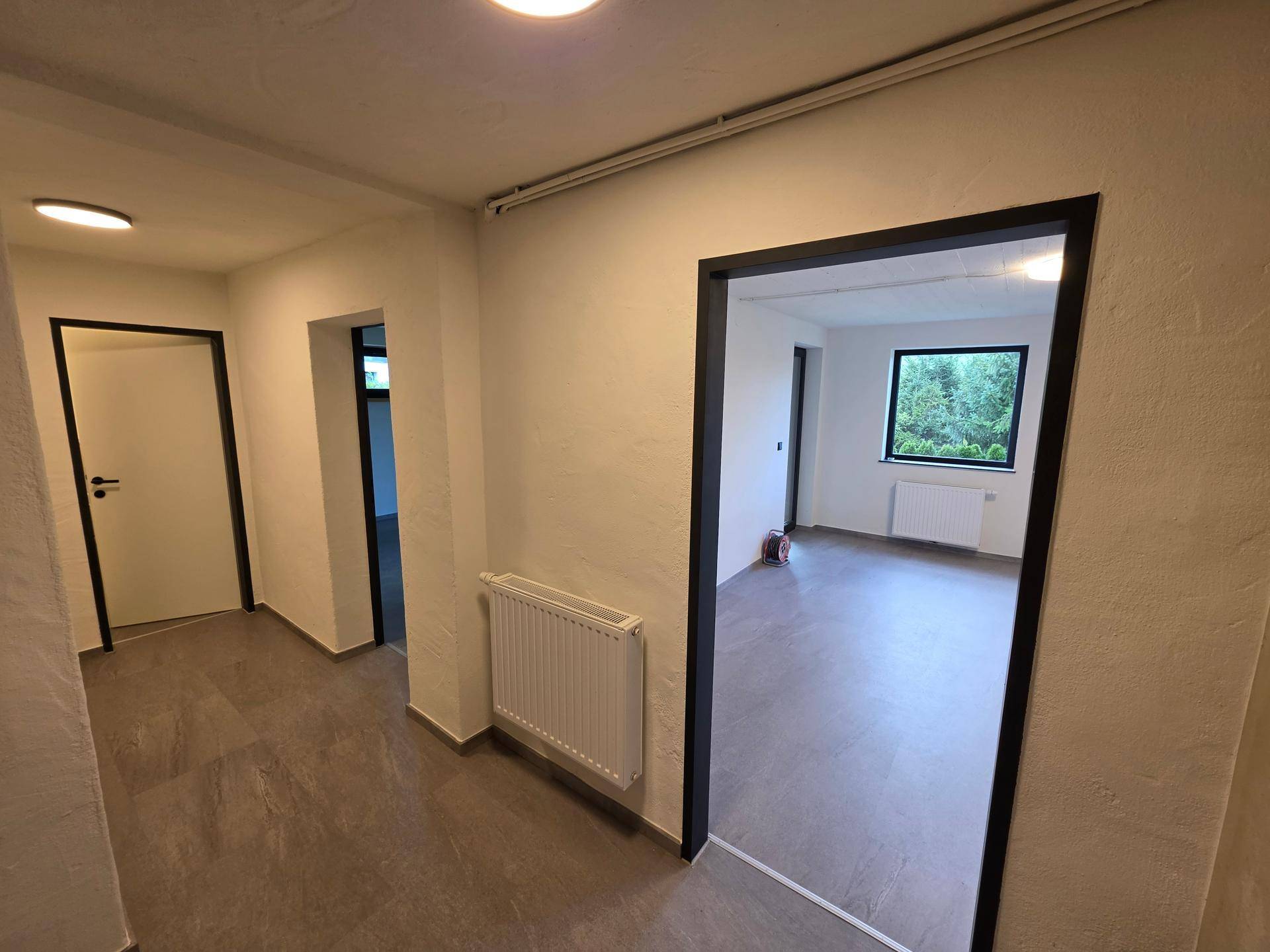 Heller Flur im Untergeschoss mit Fliesenboden und Zugang zu verschiedenen Räumen.