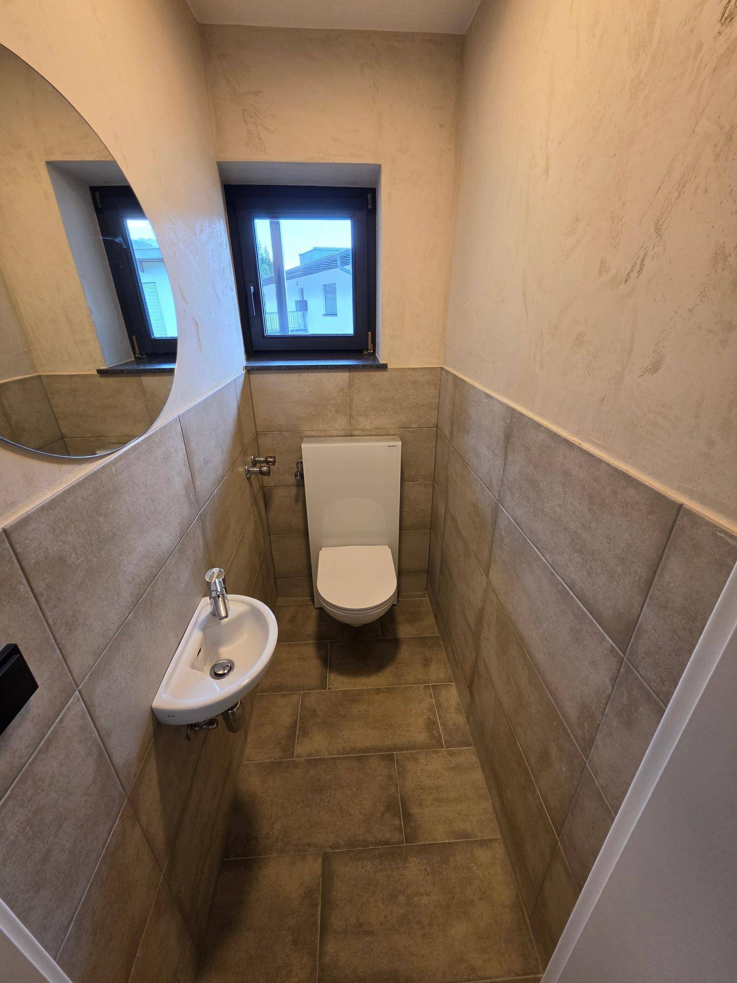 Modernes Gäste-WC mit Wand-WC, kleinem Waschbecken und Fenster.
