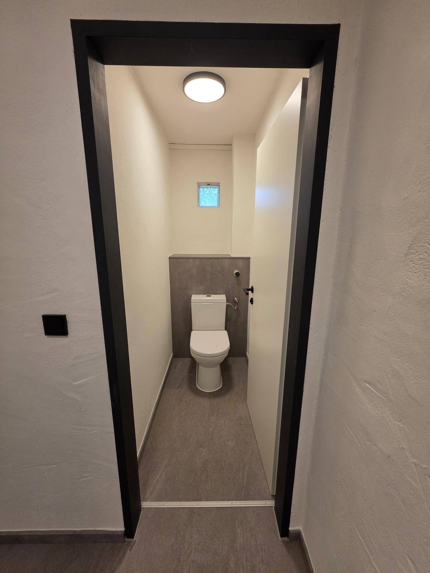 Kleines, modernes WC mit Wand-WC und kleinem Fenster für natürliche Belüftung.