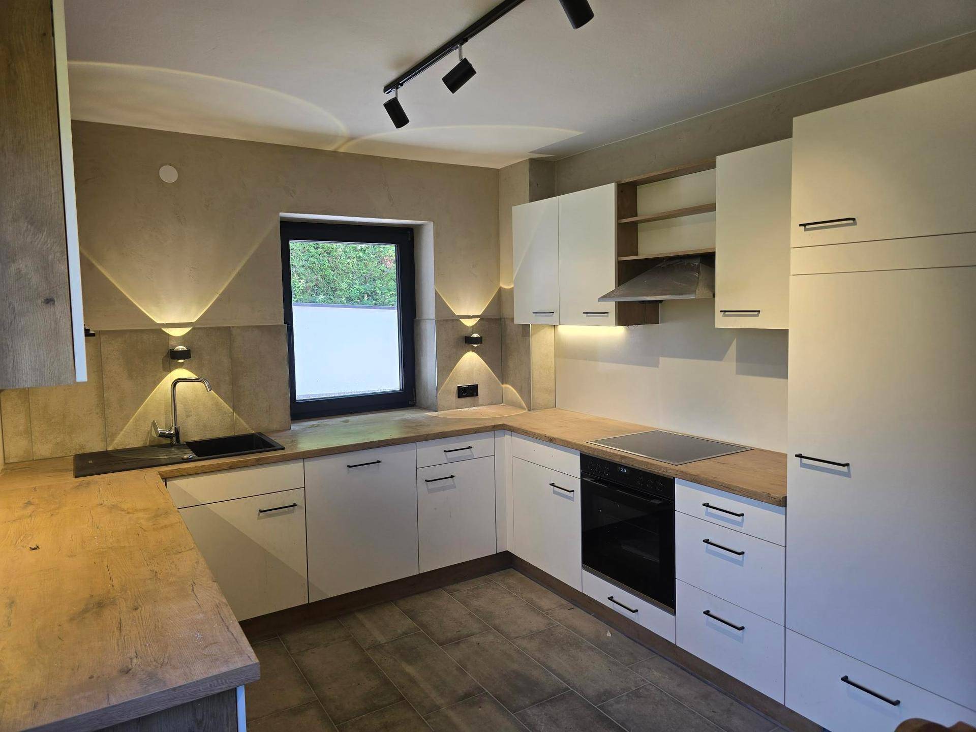 Moderne Einbauküche mit weißen Schränken, Holz-Arbeitsplatten und integrierten Geräten.