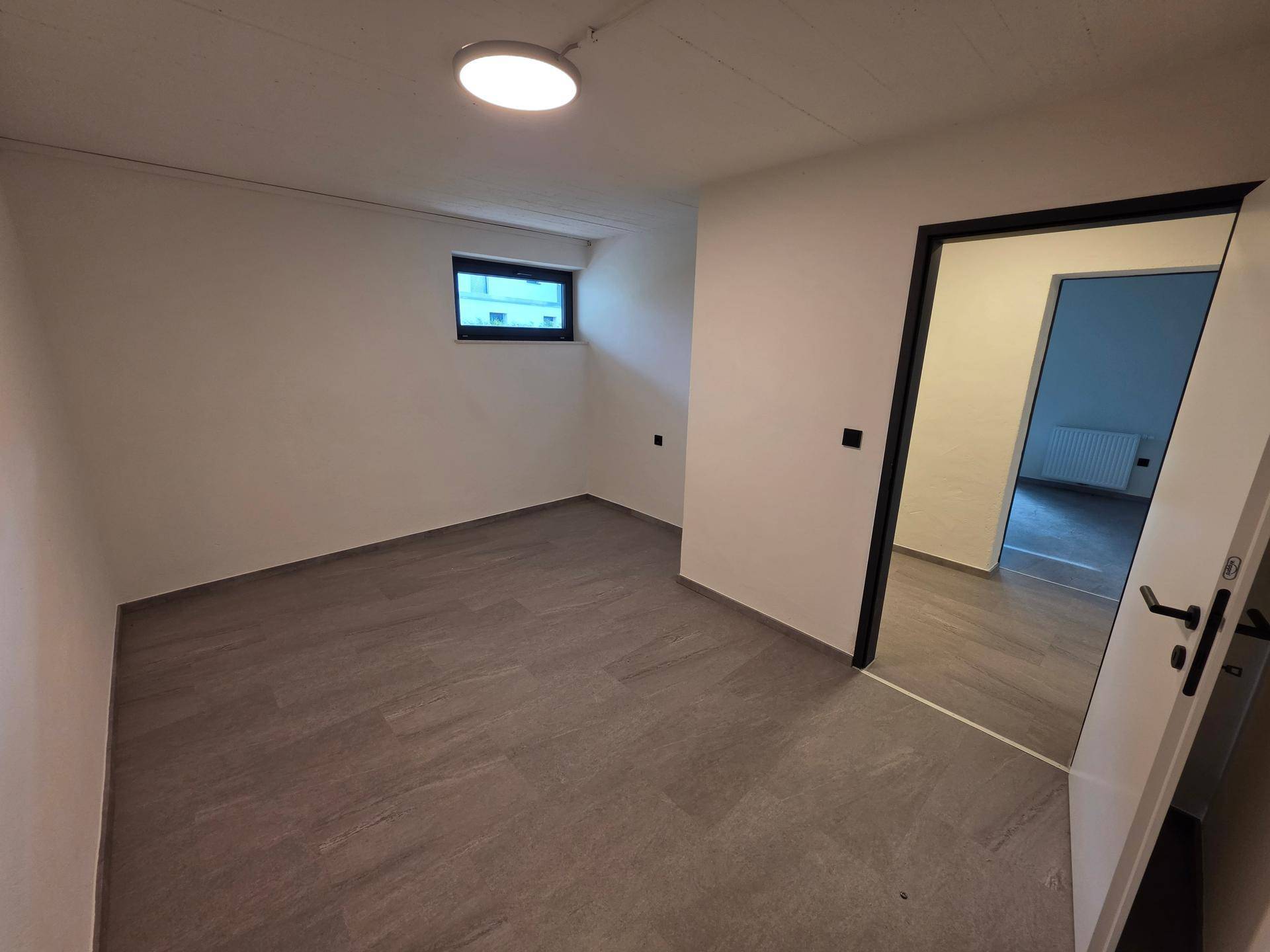 Weiterer Raum im Untergeschoss mit Fliesenboden und Zugang zu anderen Bereichen.