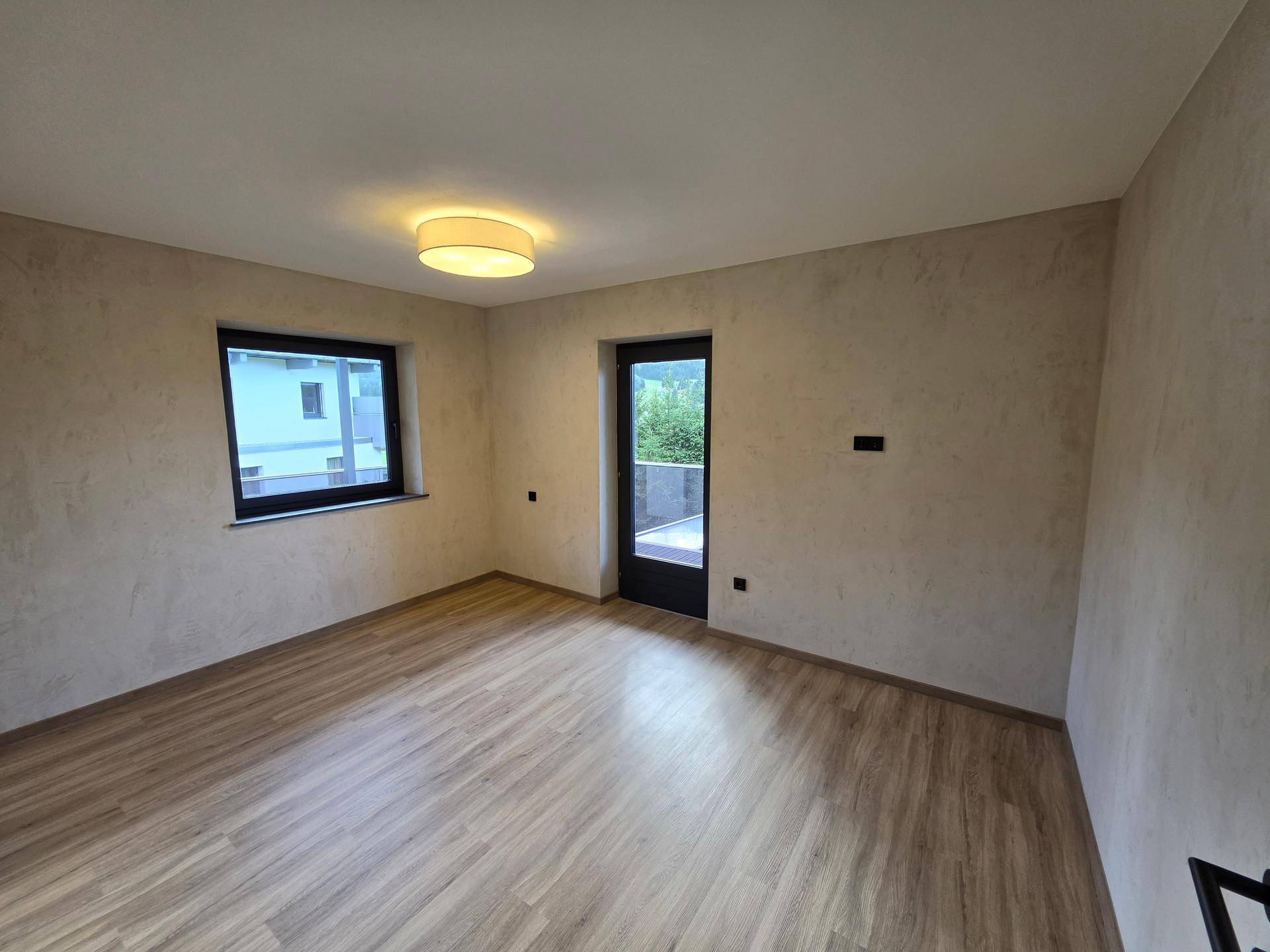 Helles Schlafzimmer mit Laminatboden und direktem Zugang zu einem Außenbereich.