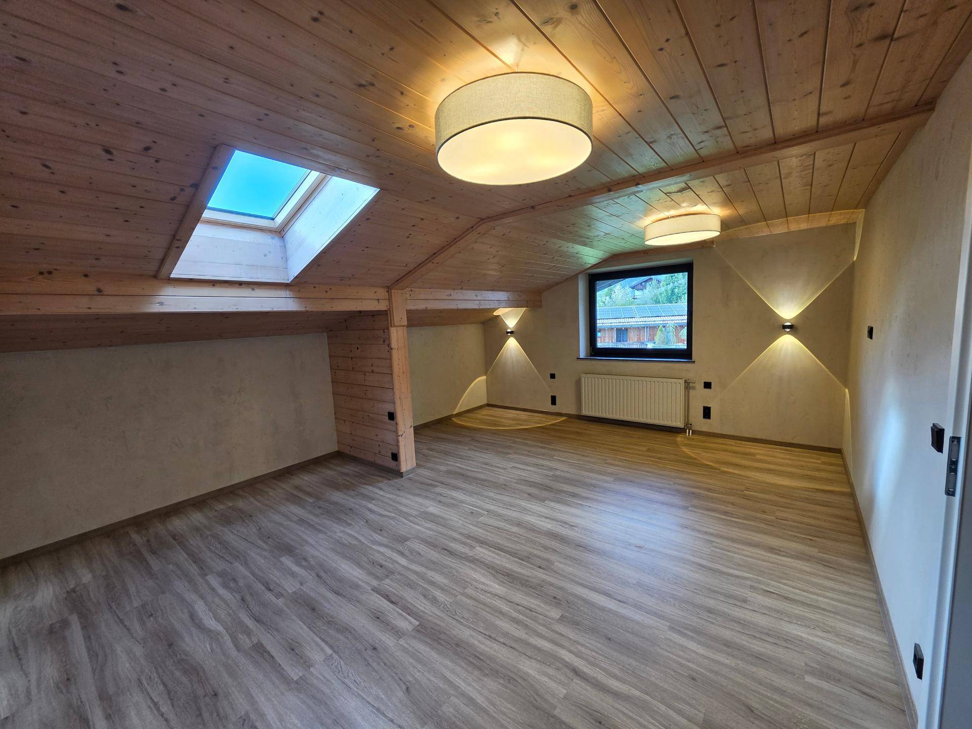 Gemütliches Schlafzimmer im Dachgeschoss mit Holzdecke, Dachfenster und Laminatboden.
