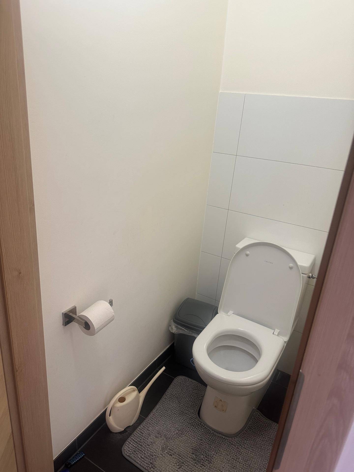Separates WC mit Toilette, Fliesen an Wand und Boden sowie einfacher Ausstattung.