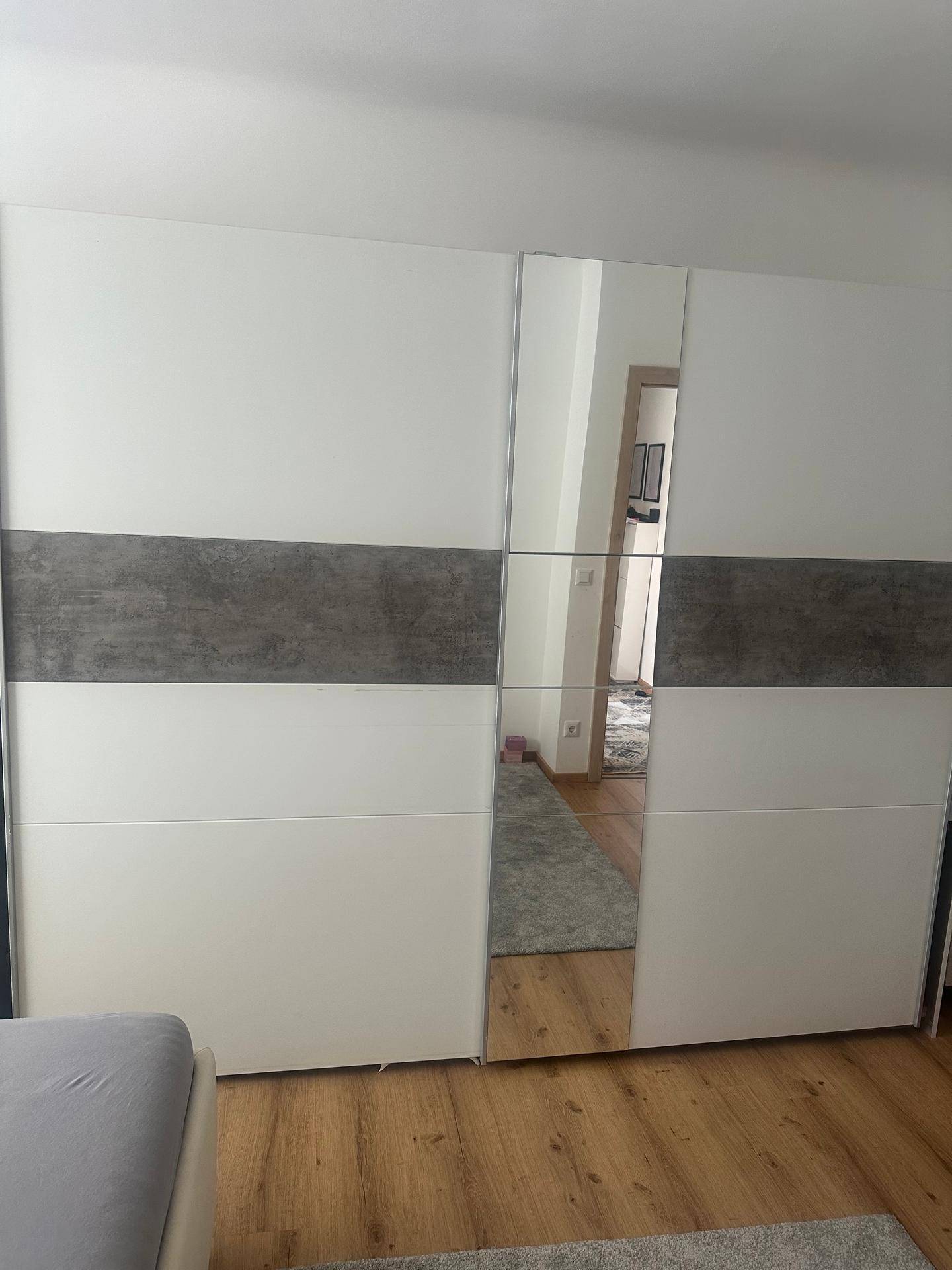 Schlafzimmer mit großem Einbauschrank mit Spiegeltüren und Holzboden.