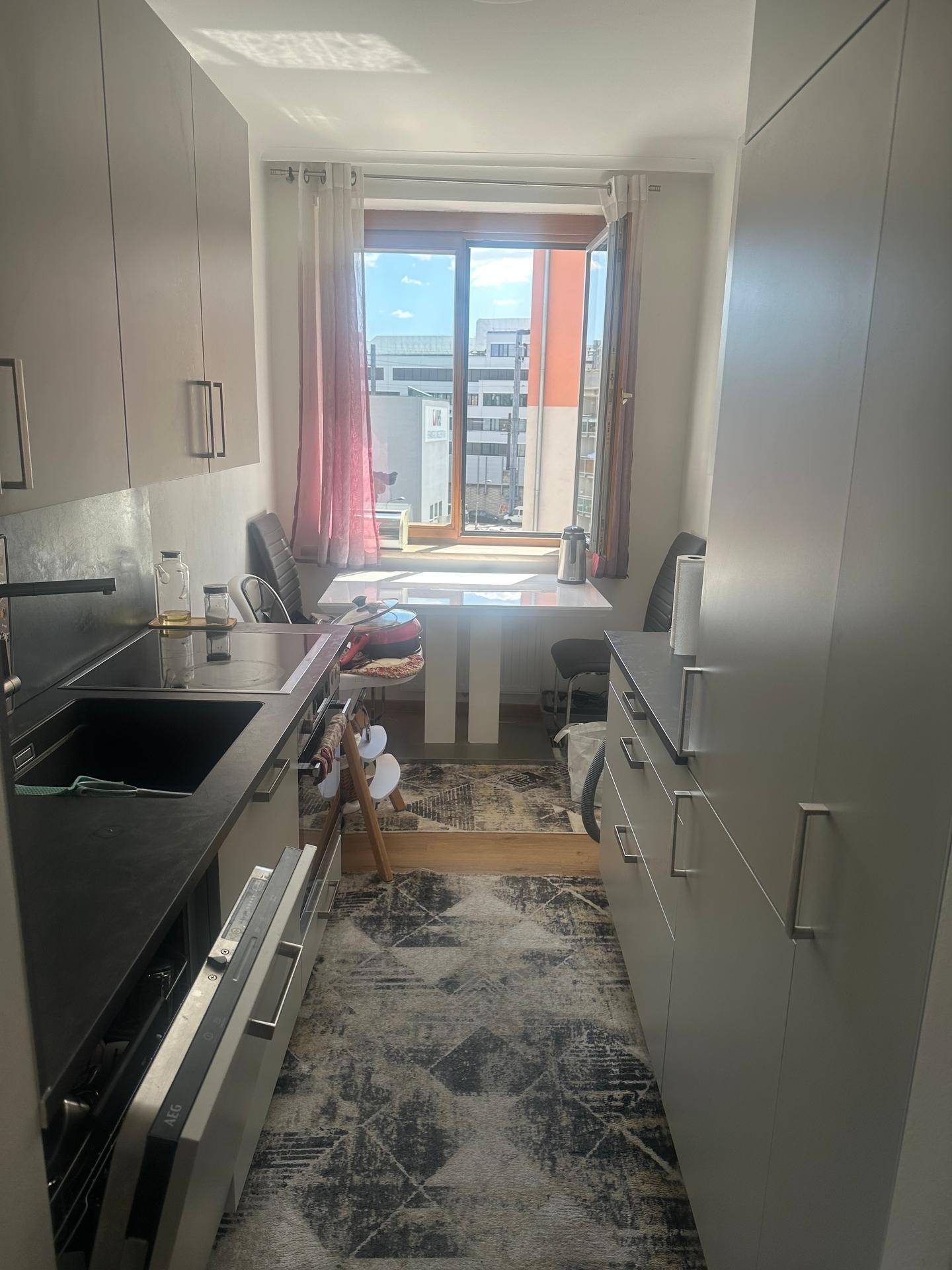 Schmale Küche mit Einbauküche, Essbereich am Fenster und Blick auf die Stadt.