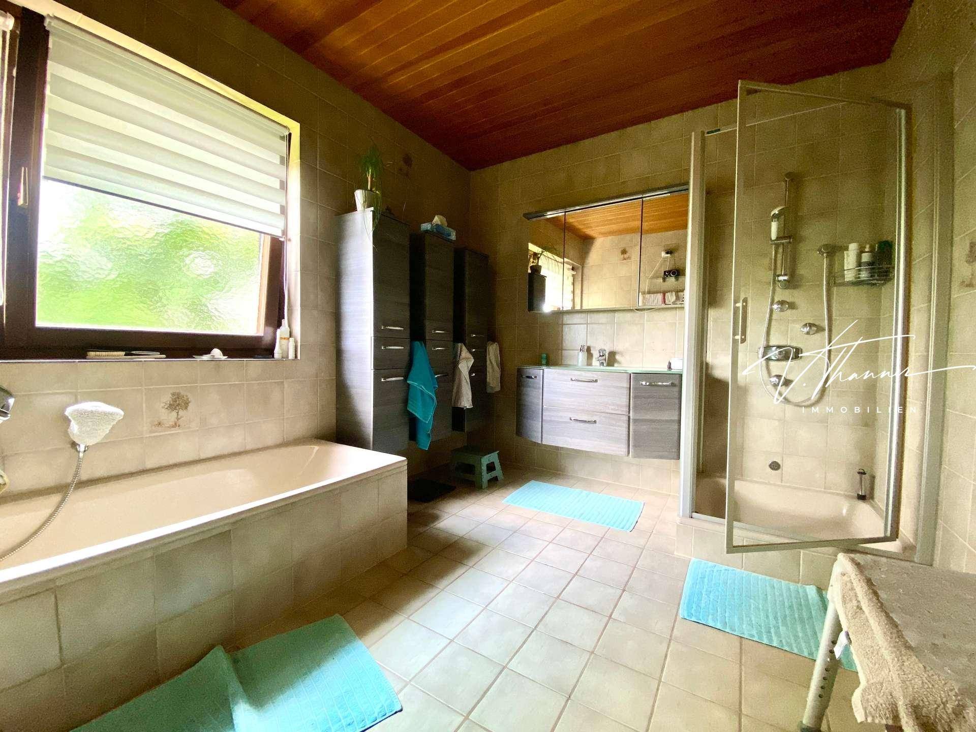 Geräumiges Badezimmer mit Badewanne, Dusche, Doppelwaschbecken und Fenster.
