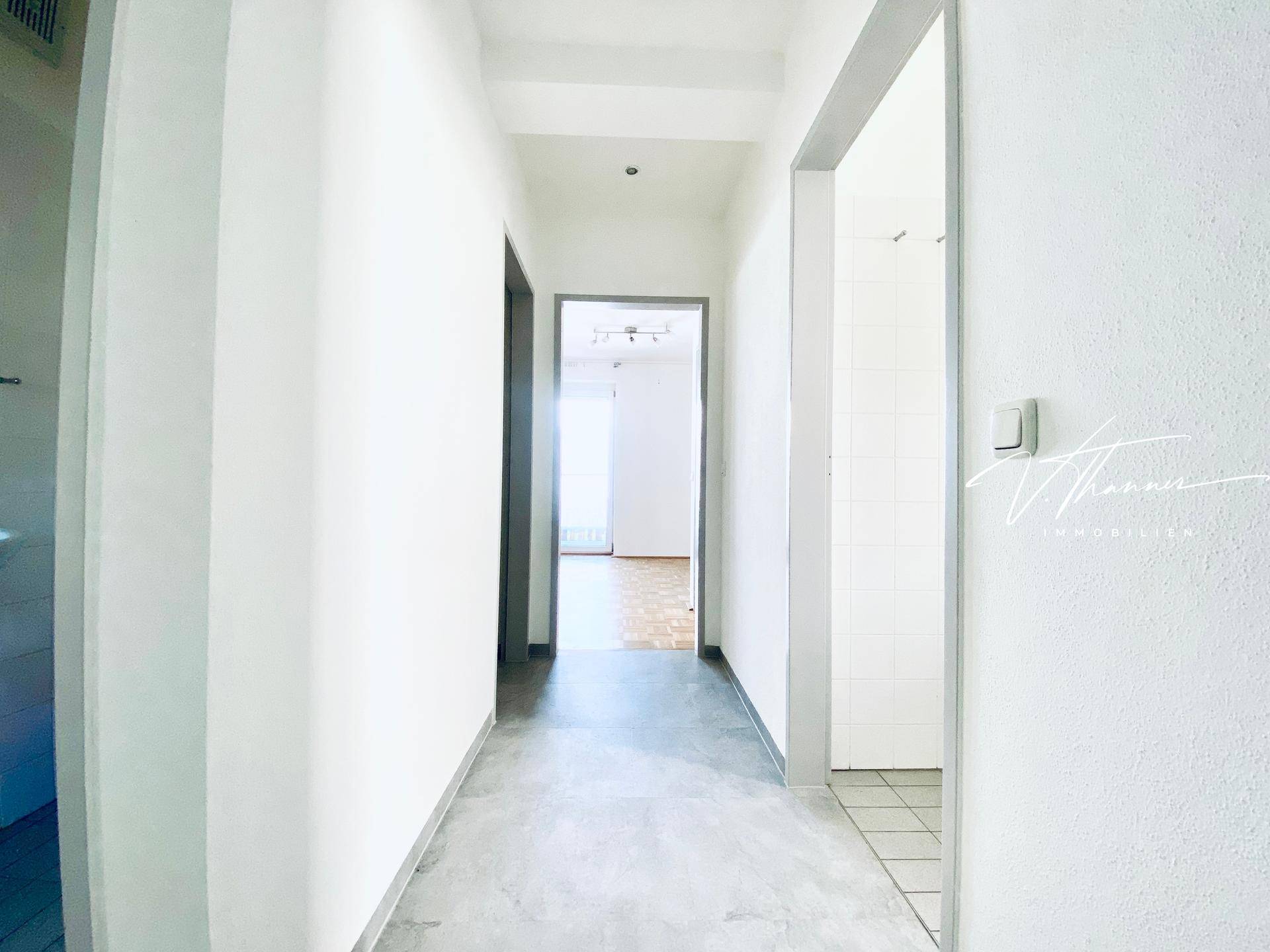 Langer, heller Flur mit modernem Bodenbelag und Zugang zu verschiedenen Zimmern der Wohnung.