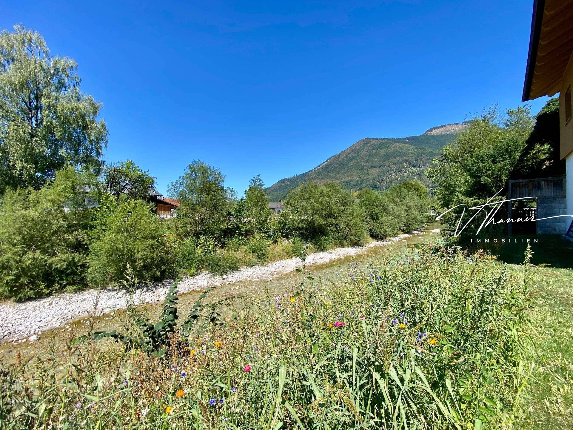 Malerischer Blick auf den Fluss und die umliegende Berglandschaft an einem sonnigen Tag.