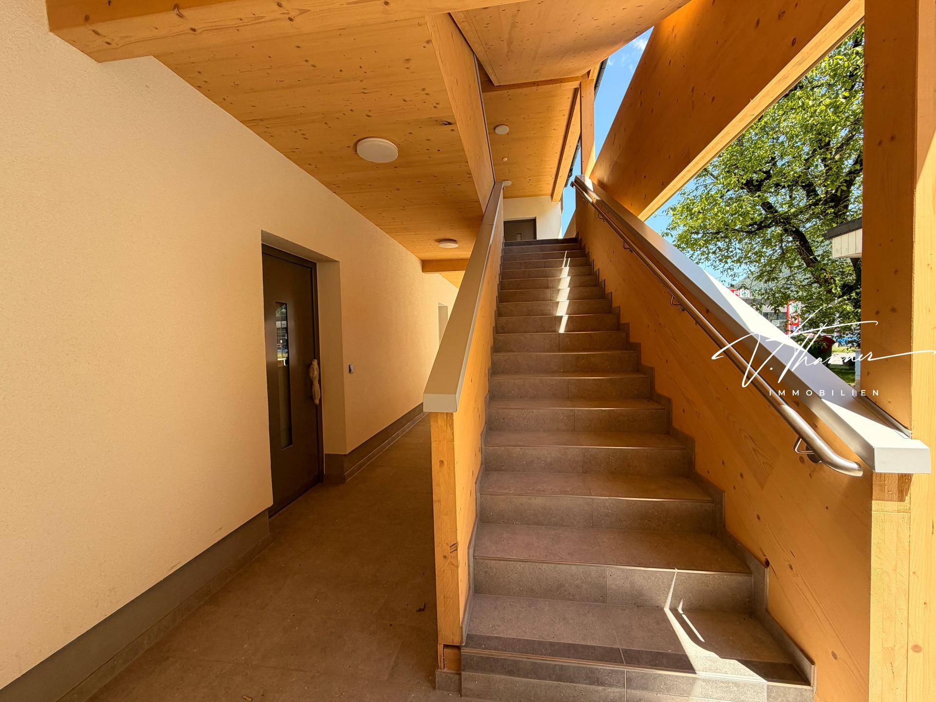 Heller Treppenaufgang mit Holzverkleidung und modernen Stufen in einem Neubau.