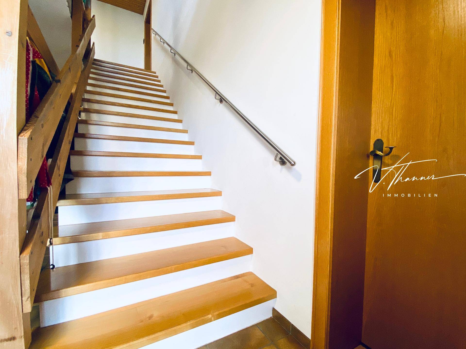 Holztreppe mit weiß gestrichenen Setzstufen und einem schlichten Handlauf.
