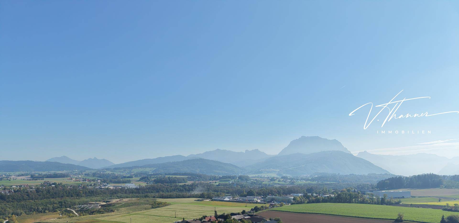 Weitläufiger Panoramablick auf die umliegende Landschaft mit Bergen und grünen Feldern.