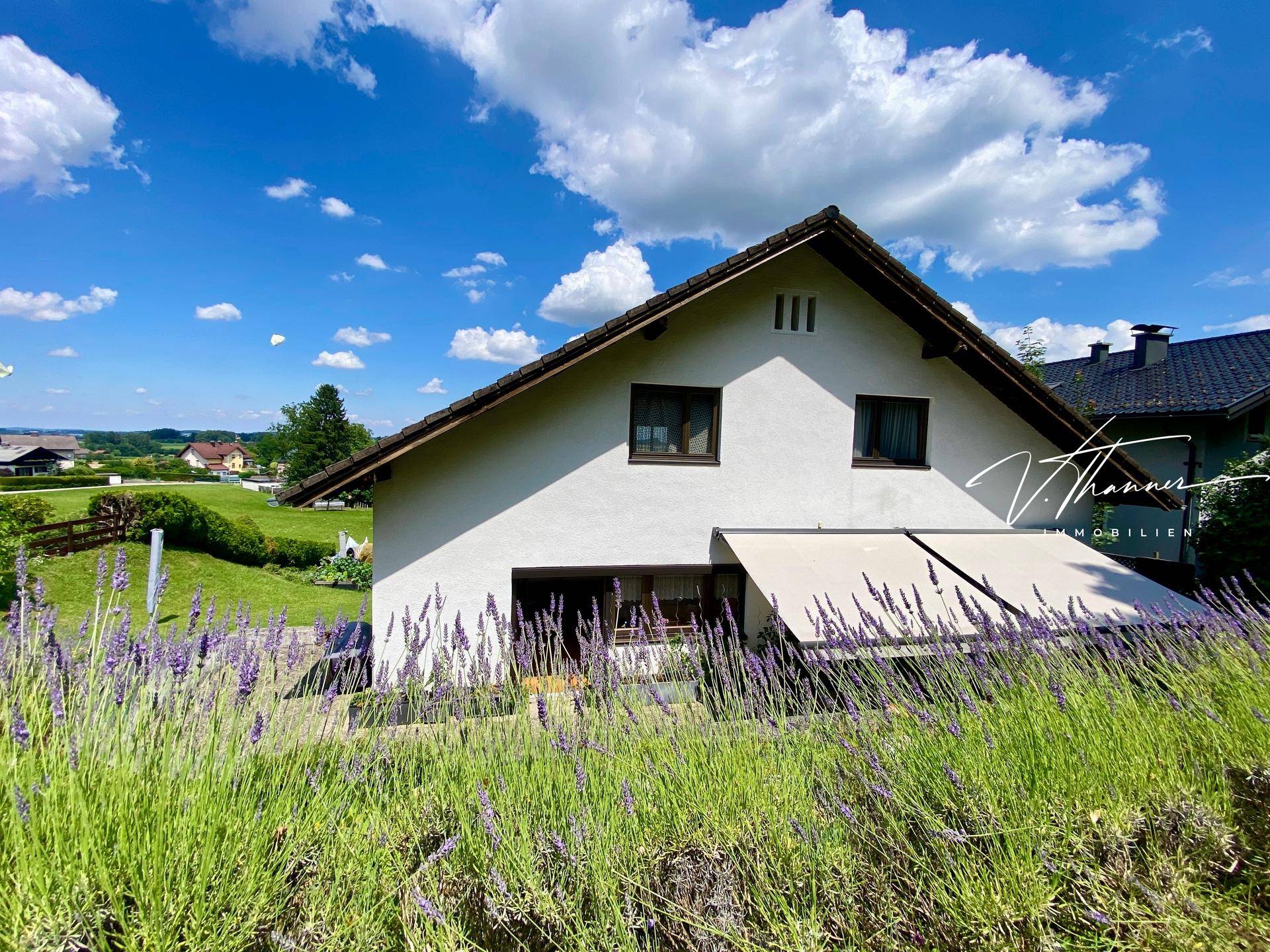 Ansicht des weißen Hauses mit Ziegeldach, umgeben von blühendem Lavendel und weitem Blick ins Grüne.