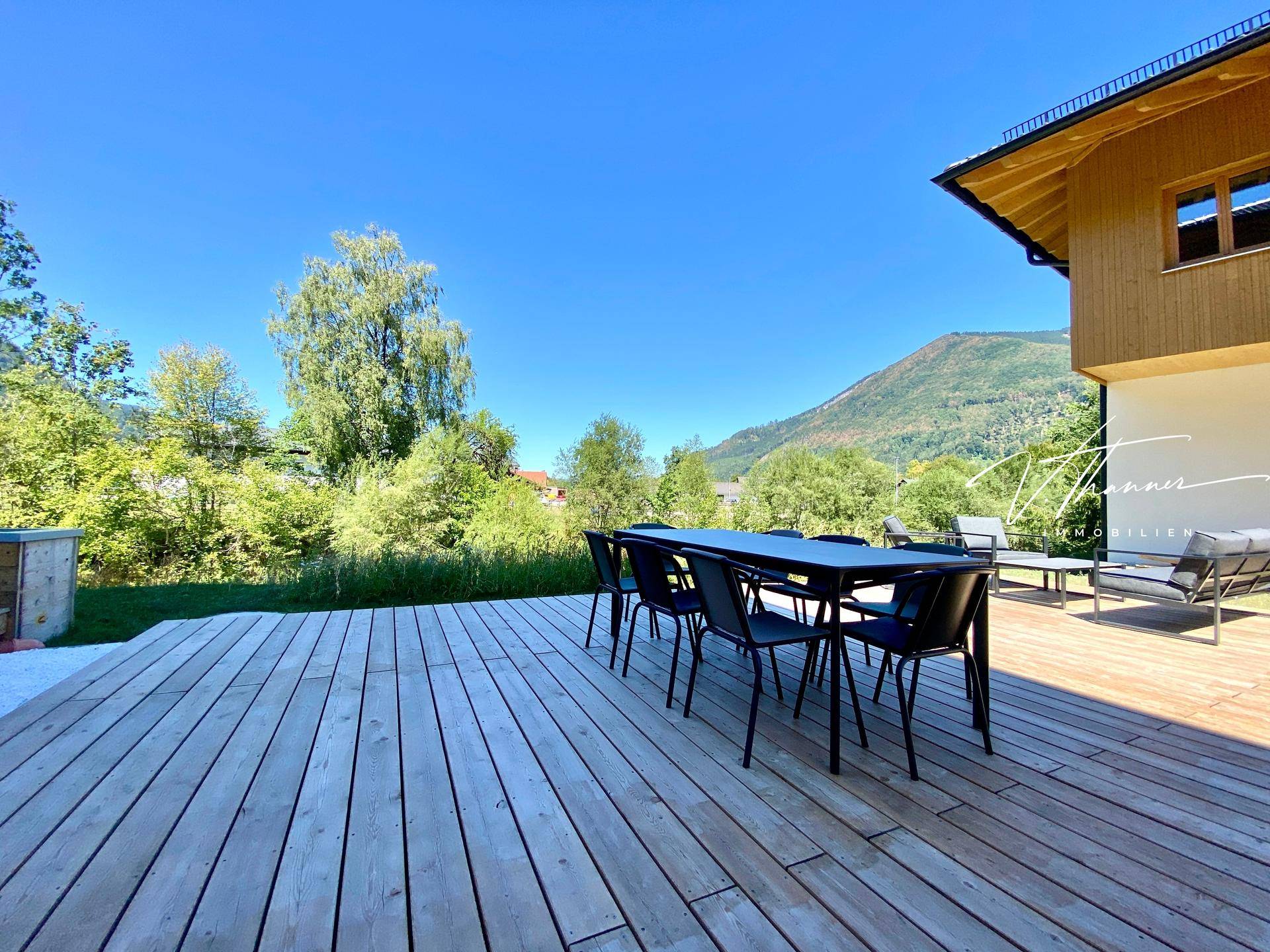 Große Holzterrasse mit Esstisch und Stühlen, ideal für Mahlzeiten im Freien mit Bergblick.