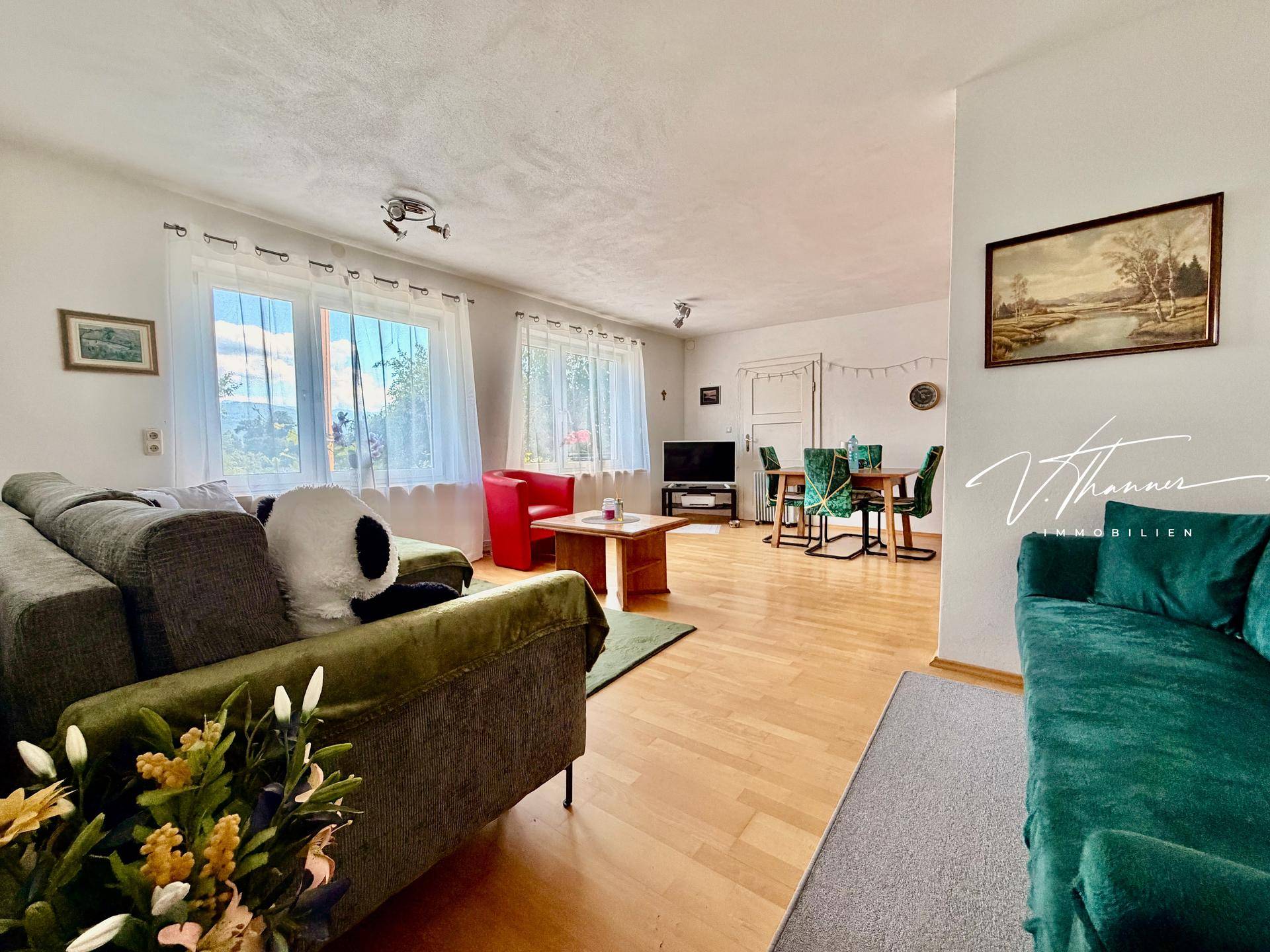 Helles Wohn-Esszimmer mit Parkettboden, gemütlichen Sofas und einem Essbereich im Hintergrund.