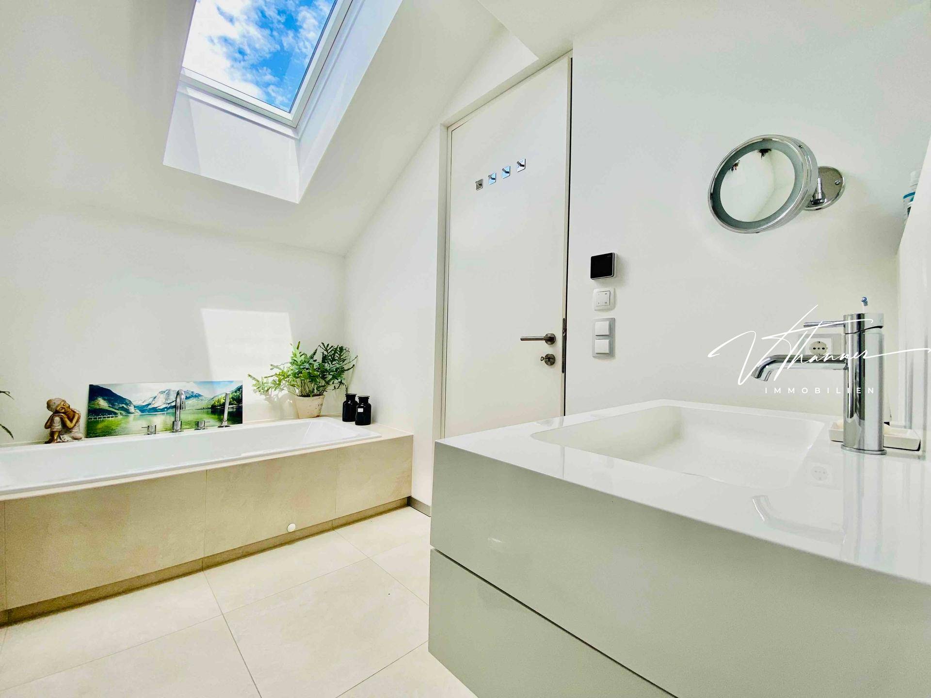 Modernes Badezimmer mit Badewanne, Dachfenster und minimalistischem Design.