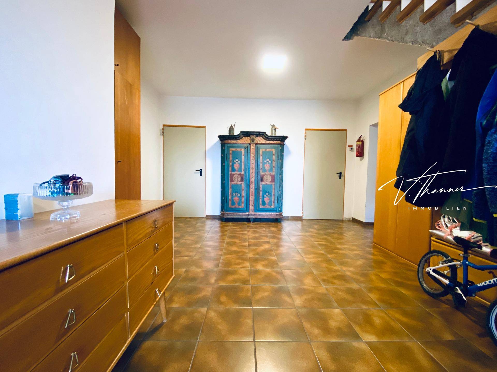 Geräumiger Flur mit Fliesenboden, Holzmöbeln und einem farbenfrohen Schrank.