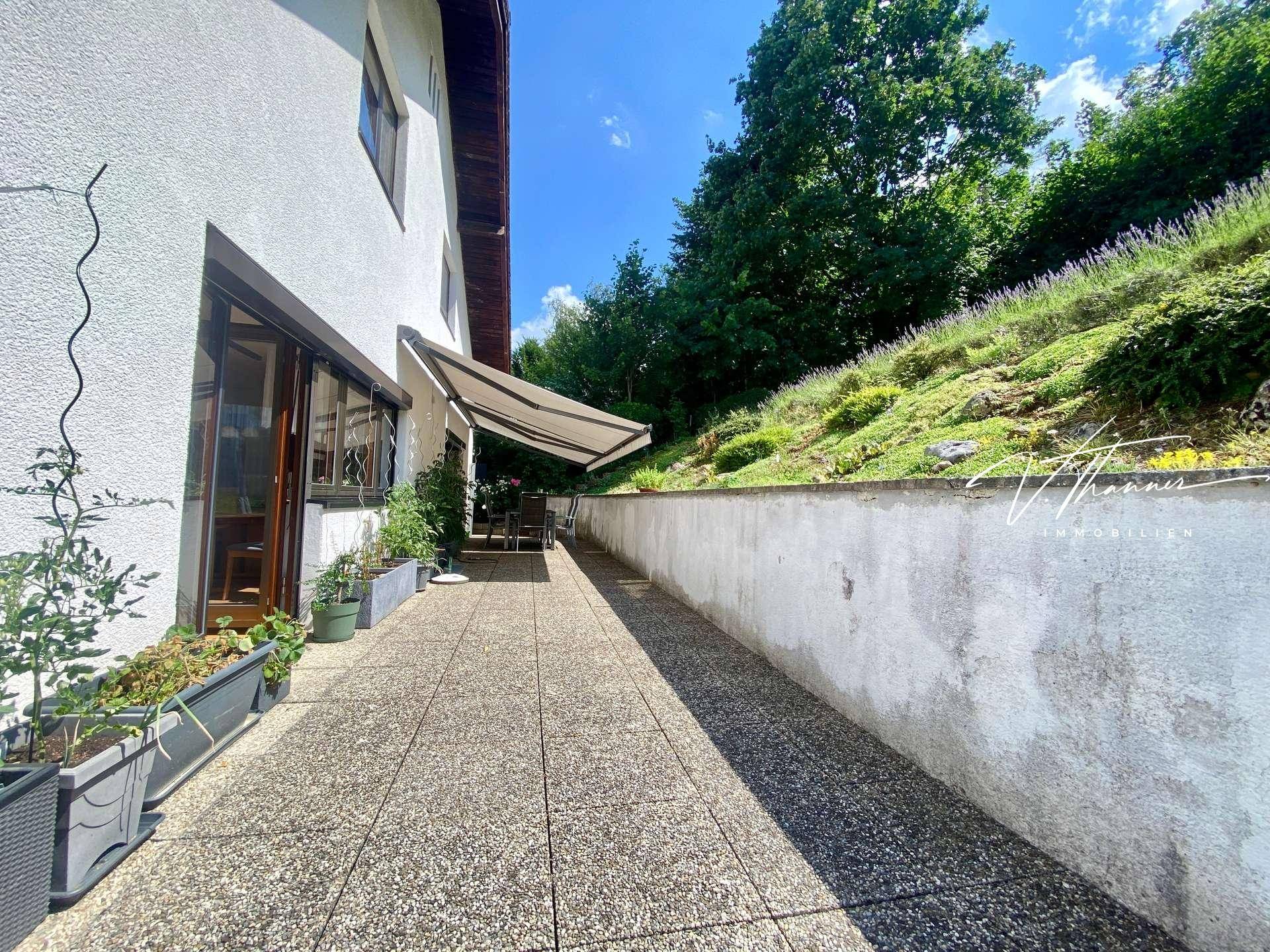 Langer, gepflasterter Terrassenbereich neben dem Haus mit Blick ins Grüne.