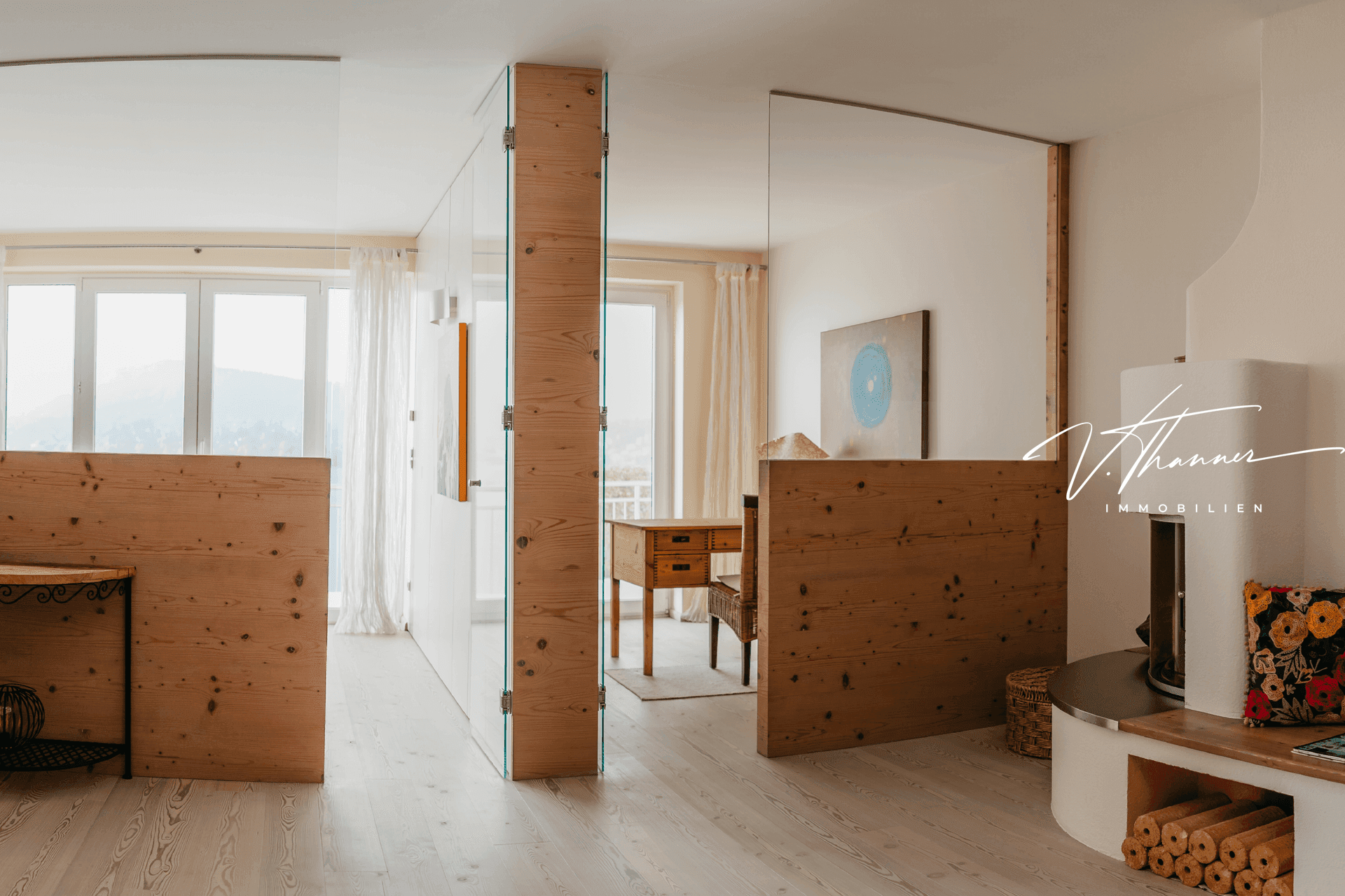 Offener Wohnbereich mit Holzelementen, Glasabtrennungen, Kamin und hellem Holzboden.
