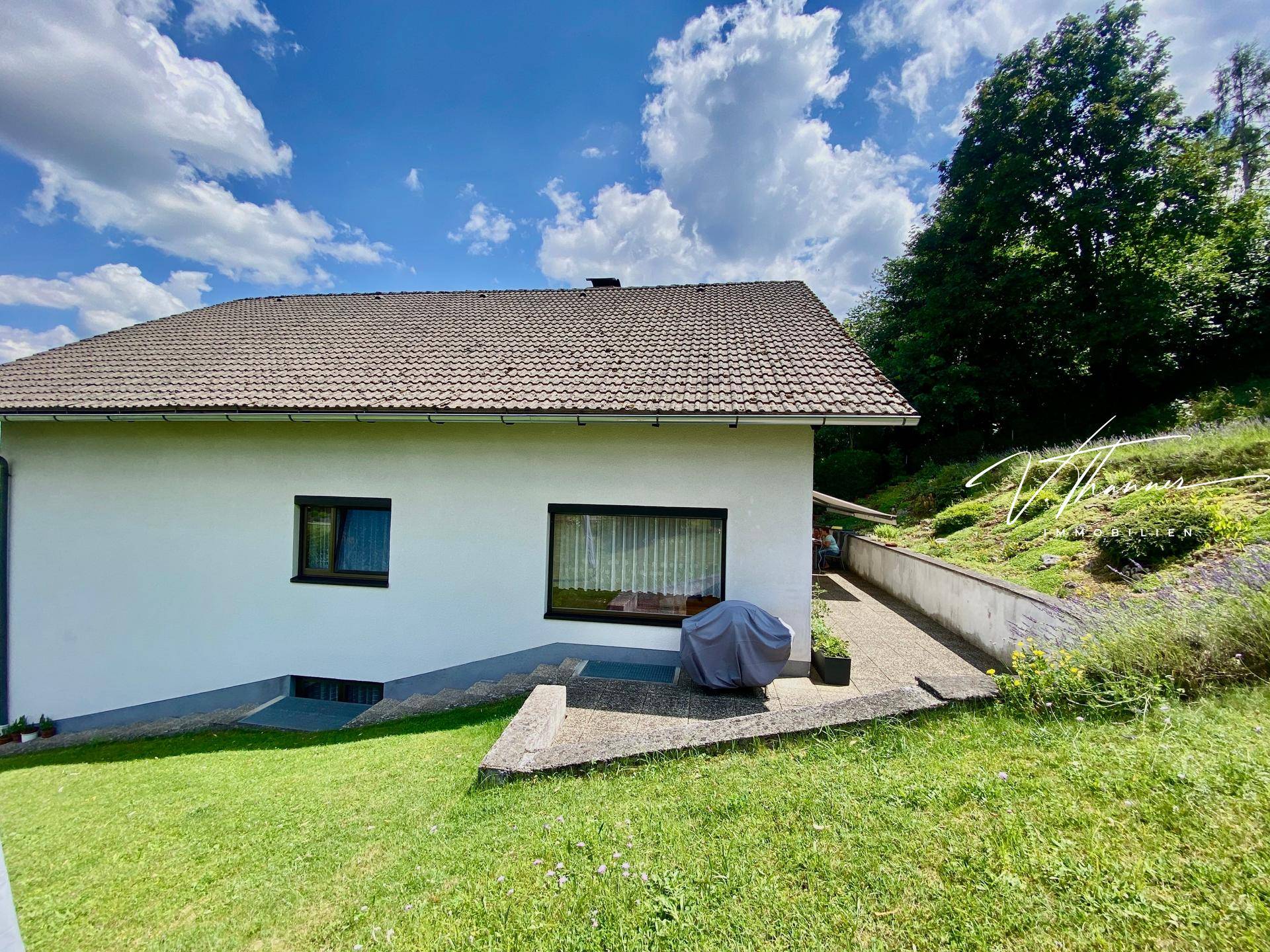 Seitenansicht des Hauses mit gepflastertem Weg und Zugang zur Terrasse im Grünen.
