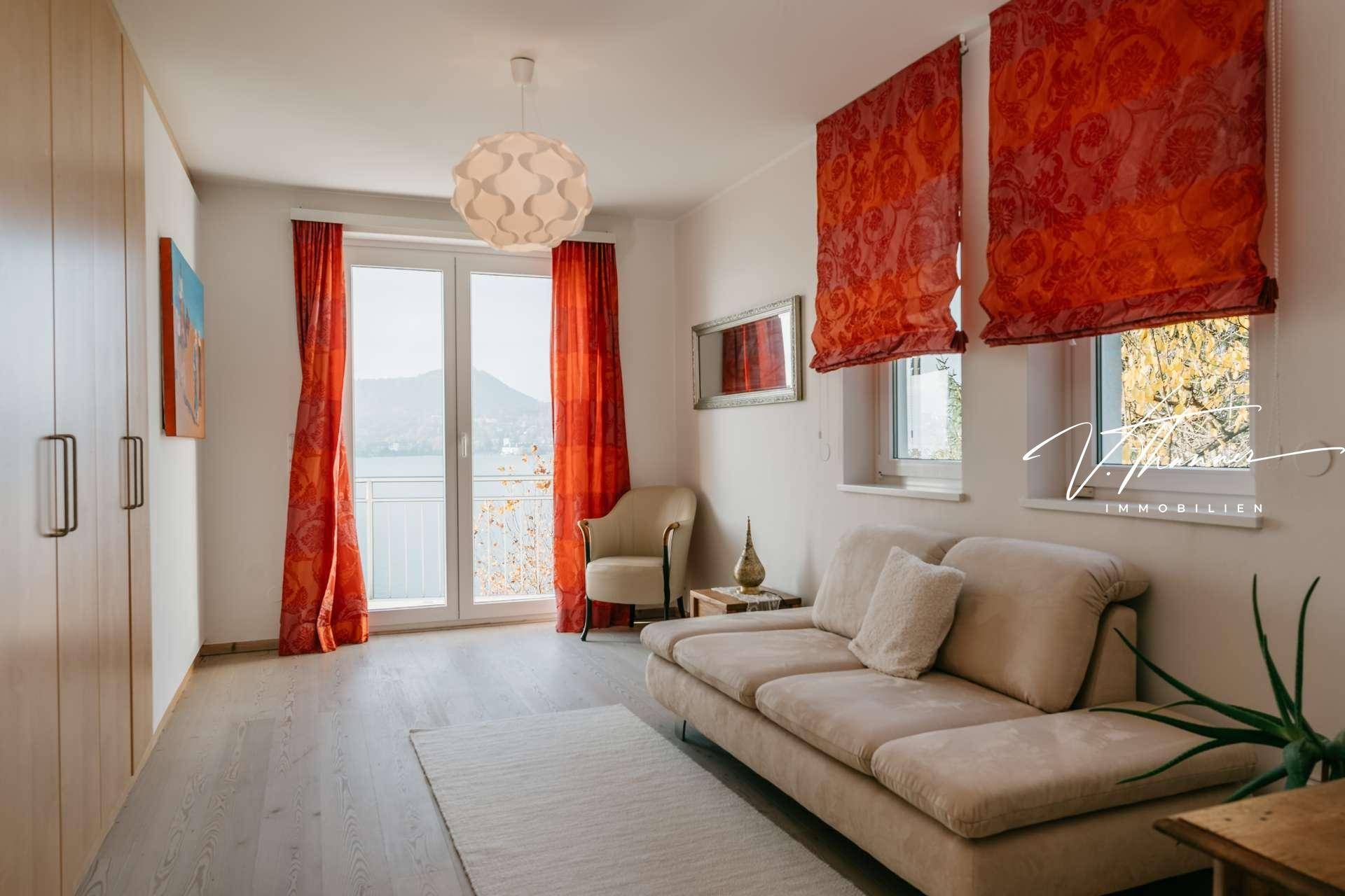 Schlafzimmer mit Sofa, Einbauschränken und Balkonzugang mit Seeblick.