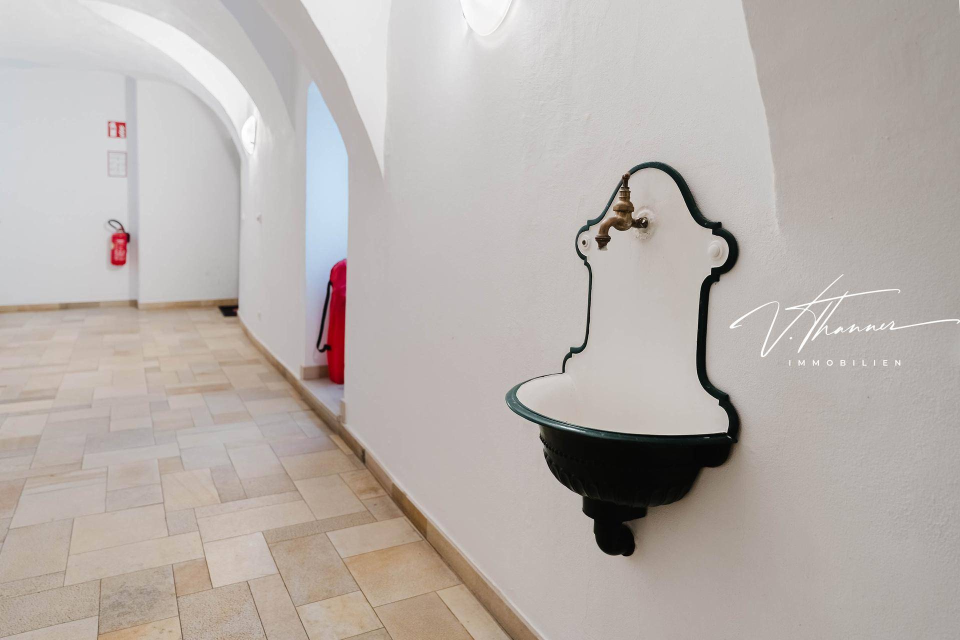 Heller Flur mit Fliesenboden und einem dekorativen Wandbrunnen im klassischen Stil.