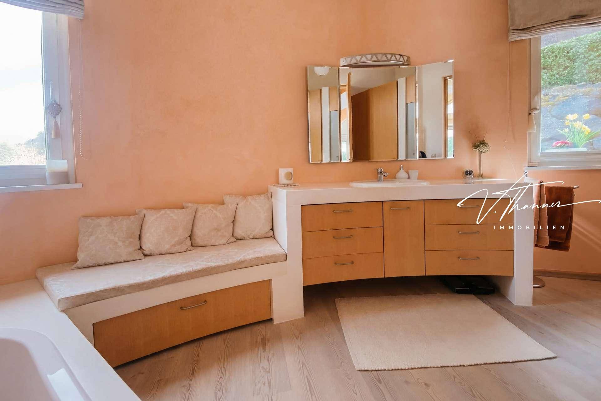 Geräumiges Badezimmer mit Doppelwaschbecken, integrierter Sitzbank und Fenster.