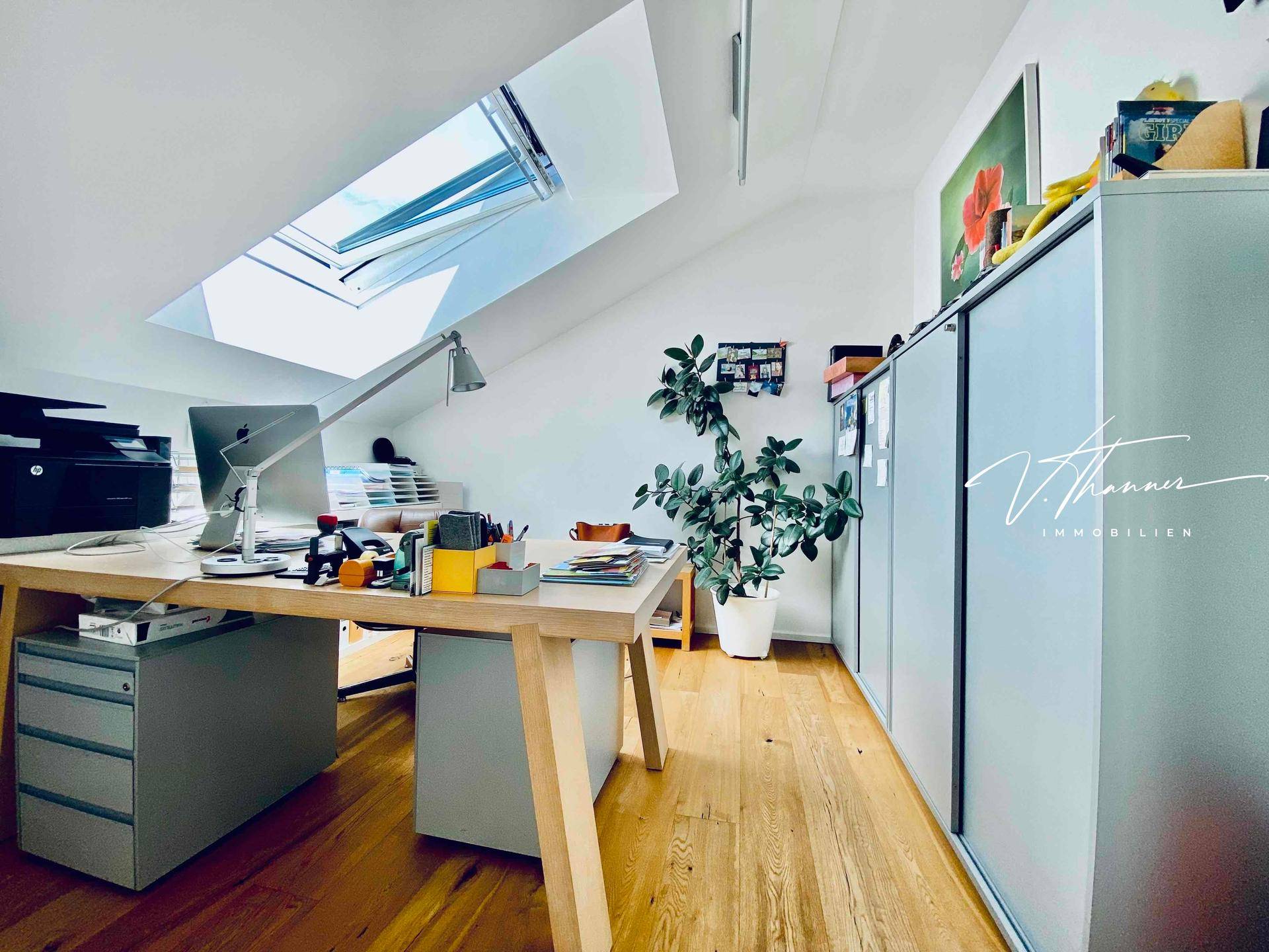 Helles Arbeitszimmer mit Dachschräge, Schreibtisch und viel Stauraum.
