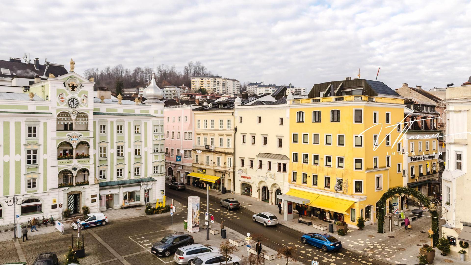 Überblick über eine belebte Stadtstraße mit historischen Gebäuden und parkenden Autos.