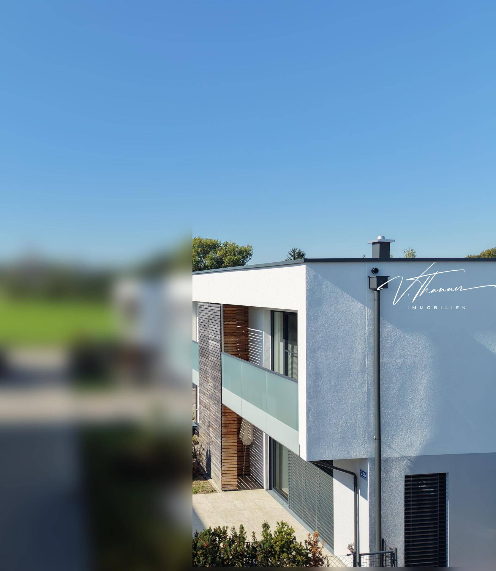 Seitenansicht des modernen Hauses mit Flachdach und klarem blauem Himmel.