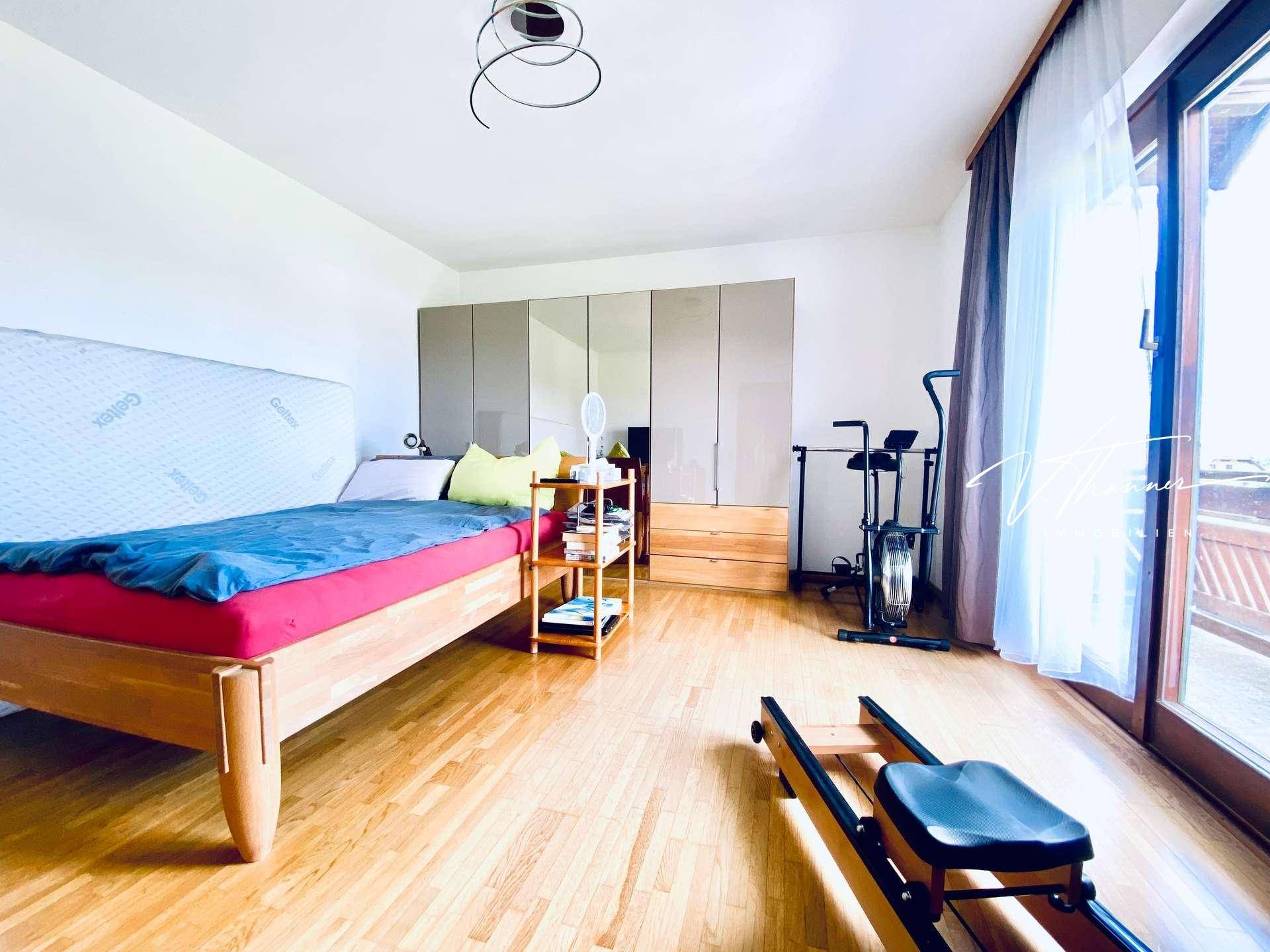 Helles Schlafzimmer mit Holzboden, großem Kleiderschrank und Zugang zum Balkon.