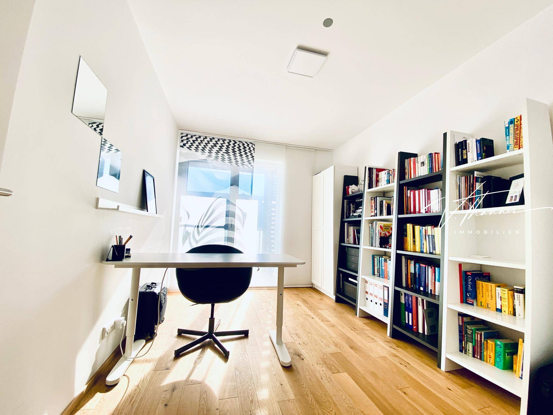 Helles Arbeitszimmer mit Schreibtisch, Bücherregalen und Parkettboden, ideal für Home-Office.