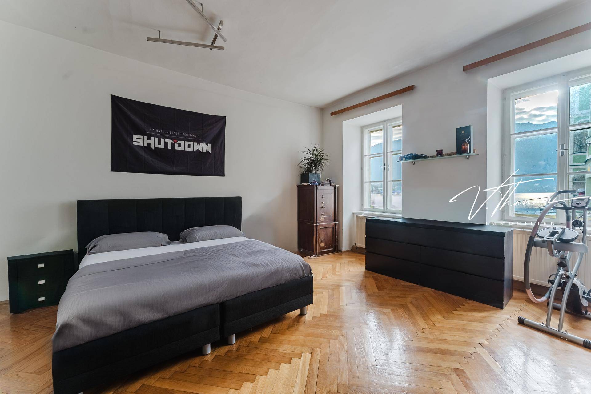 Gemütliches Schlafzimmer mit Holzboden, Doppelbett und Fenstern mit Bergblick.